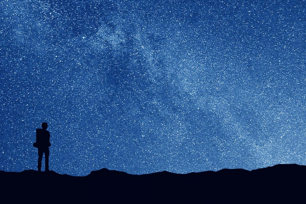 Stars 桌布 壁紙 — 一個孤獨的身影站在黑暗的山丘上，仰望滿佈銀河的廣闊星空夜空。