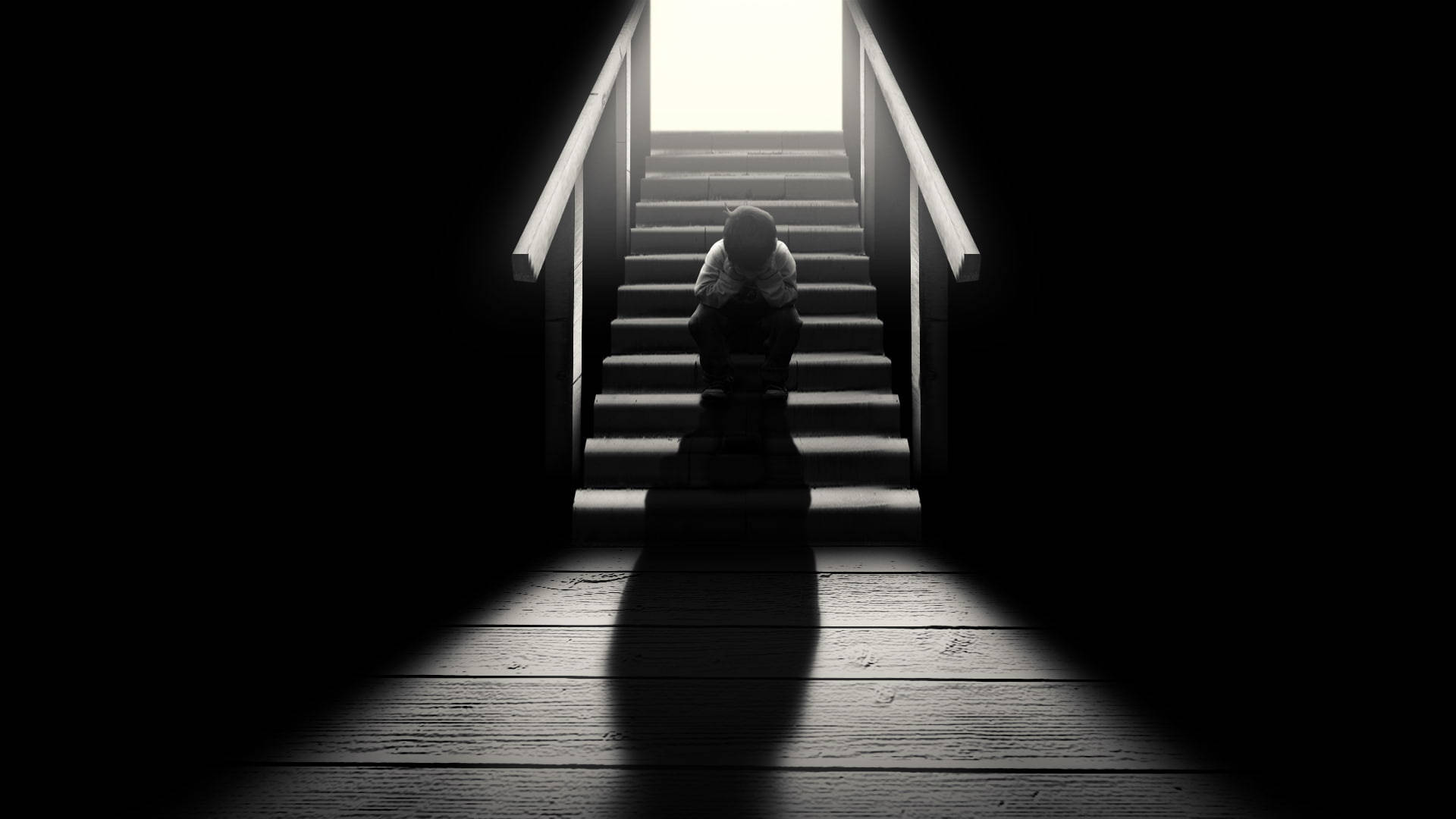 Alone Boy 桌布 壁紙 — 一個孤獨的身影蜷縮在光禿禿的樓梯底部，沐浴在戲劇性的背光中。