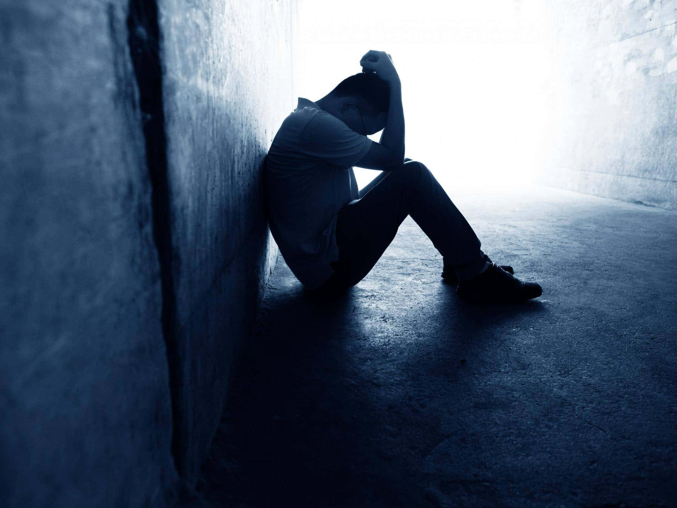 Depressed 桌布 壁紙 — 一個孤獨的身影蜷縮在昏暗隧道中的混凝土牆上，雙手掩面，充滿絕望。