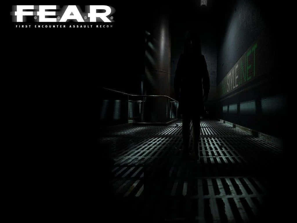 Dark Fear 桌布 壁紙 — 一個孤獨的身影走在一條黑暗的工業走廊中，牆上有發光的綠色文字，強烈的燈光投下長長的陰影。