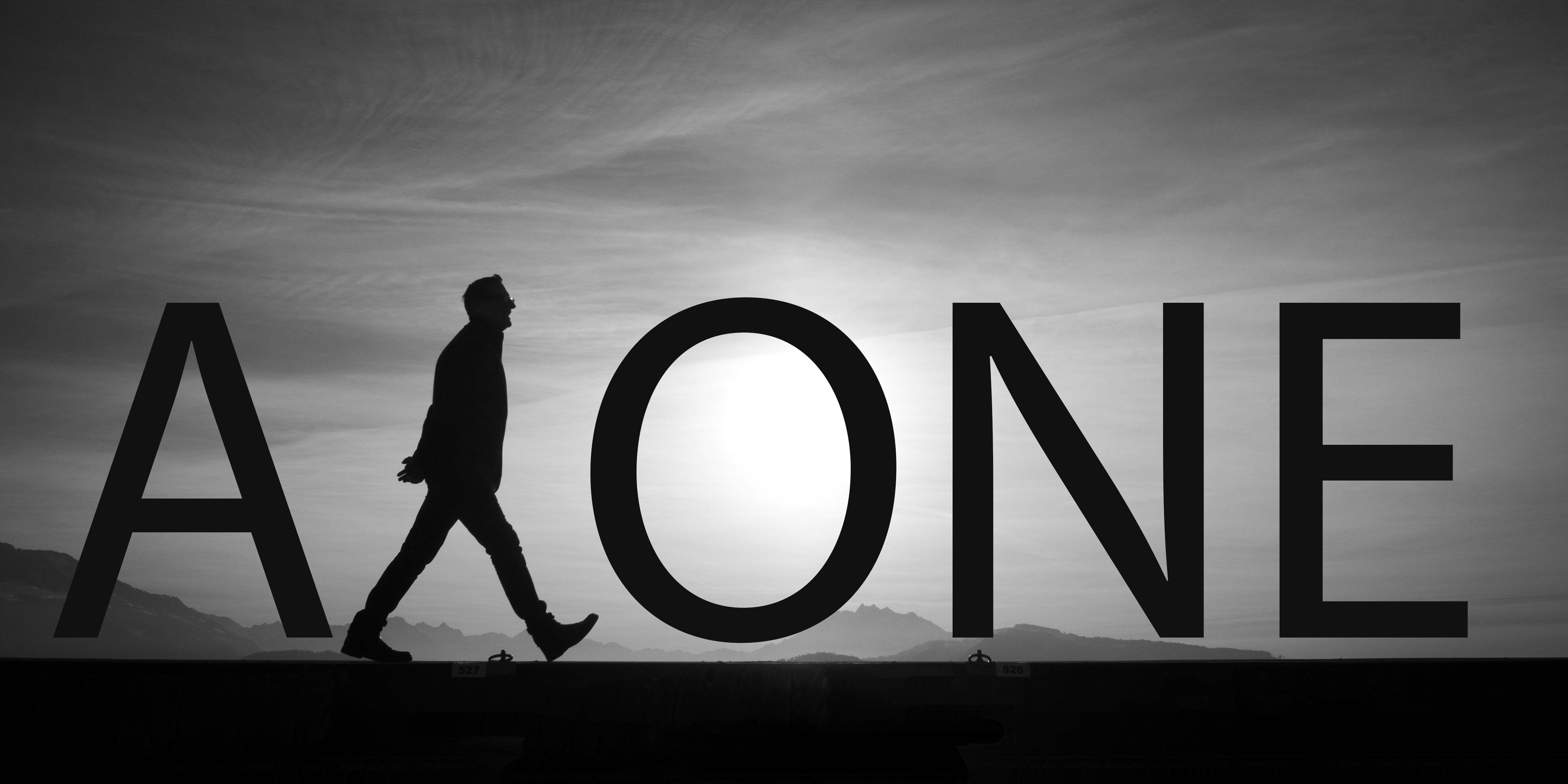 Alone 桌布 壁紙 — 一個孤獨的身影走過拼出「ALONE」的巨大粗體字母，背景是陰沉的灰色天空。