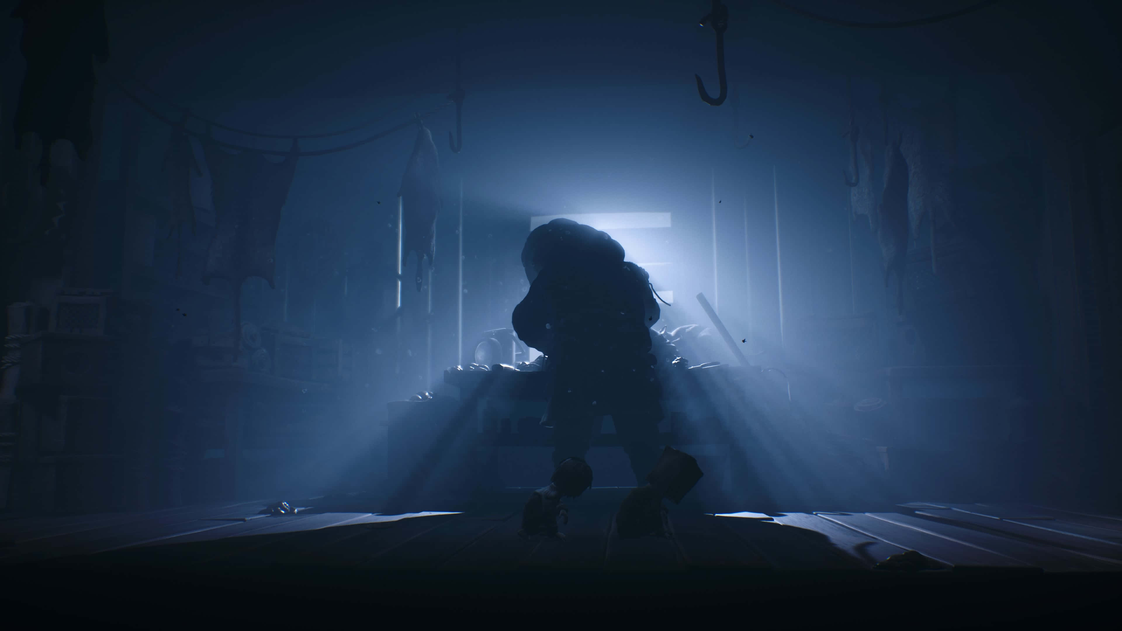Little Nightmares 4K 桌布 壁紙 — 一個孤獨的身影跪在一個光線昏暗、雜亂的房間裡，房間沐浴在從遠處窗戶透進來的冷藍光中。