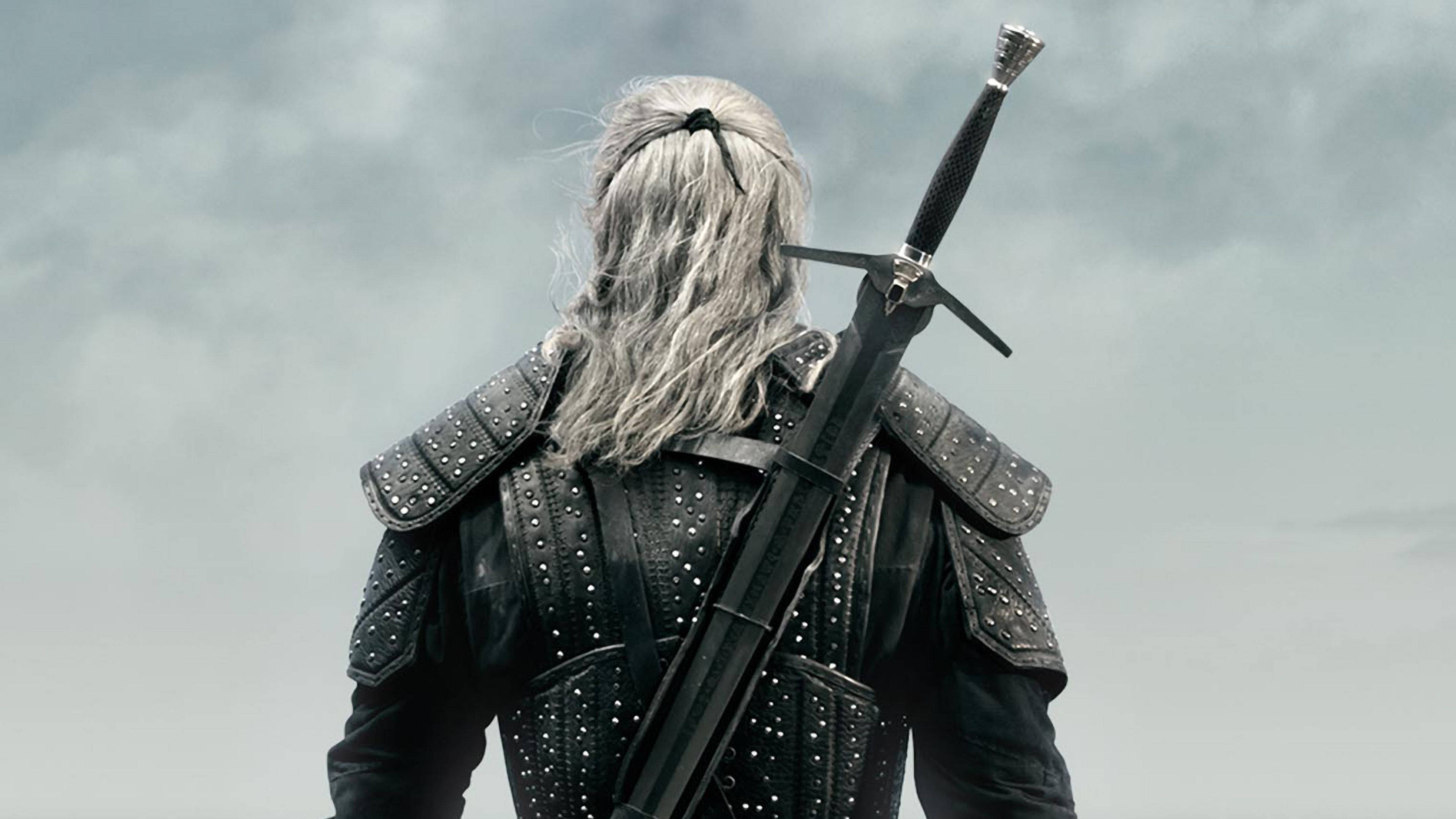 witcher 4K 桌布 壁紙 — 一個孤獨的銀髮戰士身穿黑色鉚釘盔甲，背著劍，站在多雲的天空下。