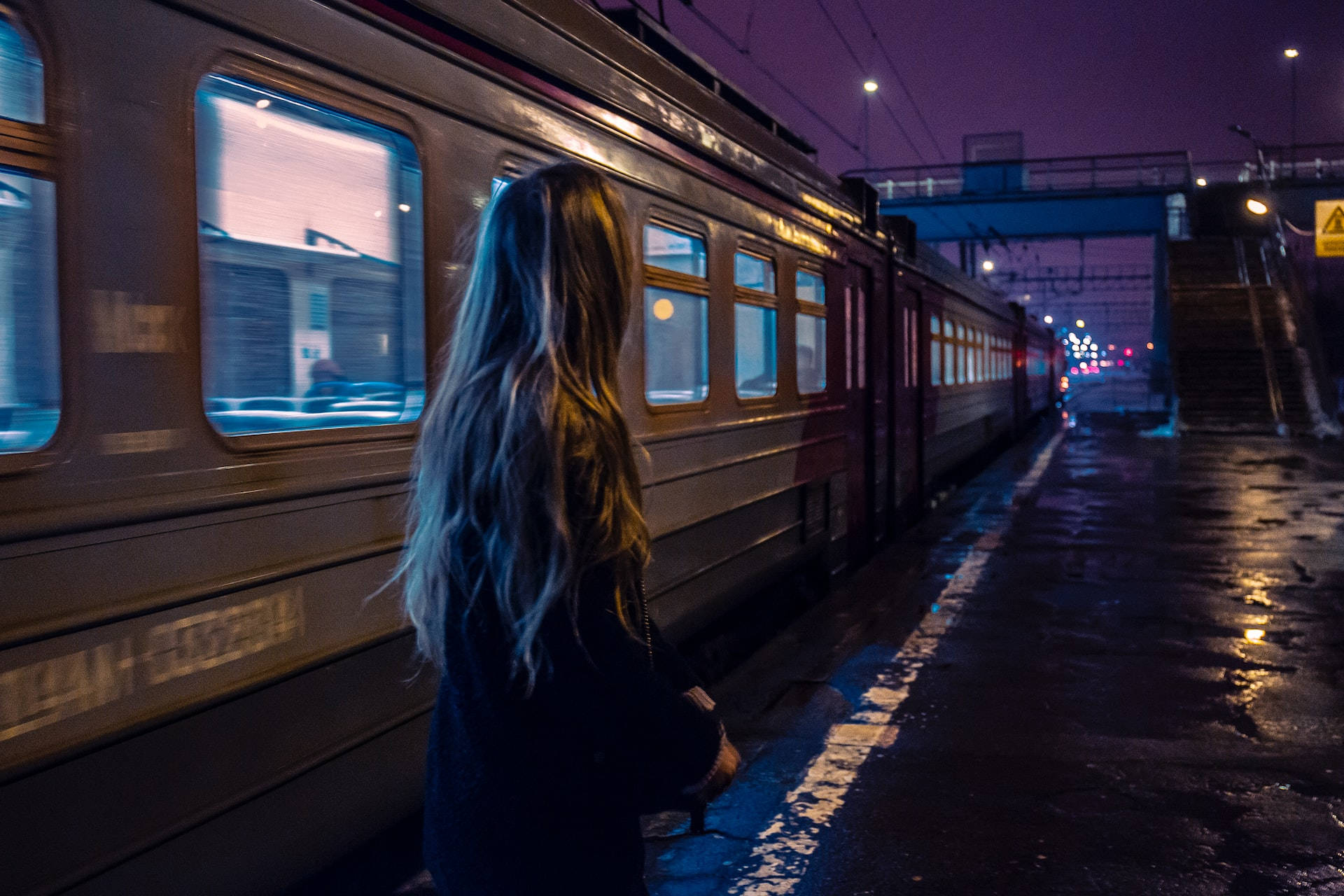 火車 桌布 壁紙 — 一個孤獨的長髮女子夜晚站在濕漉漉的火車月台上，看著火車在紫色暮色中駛過。