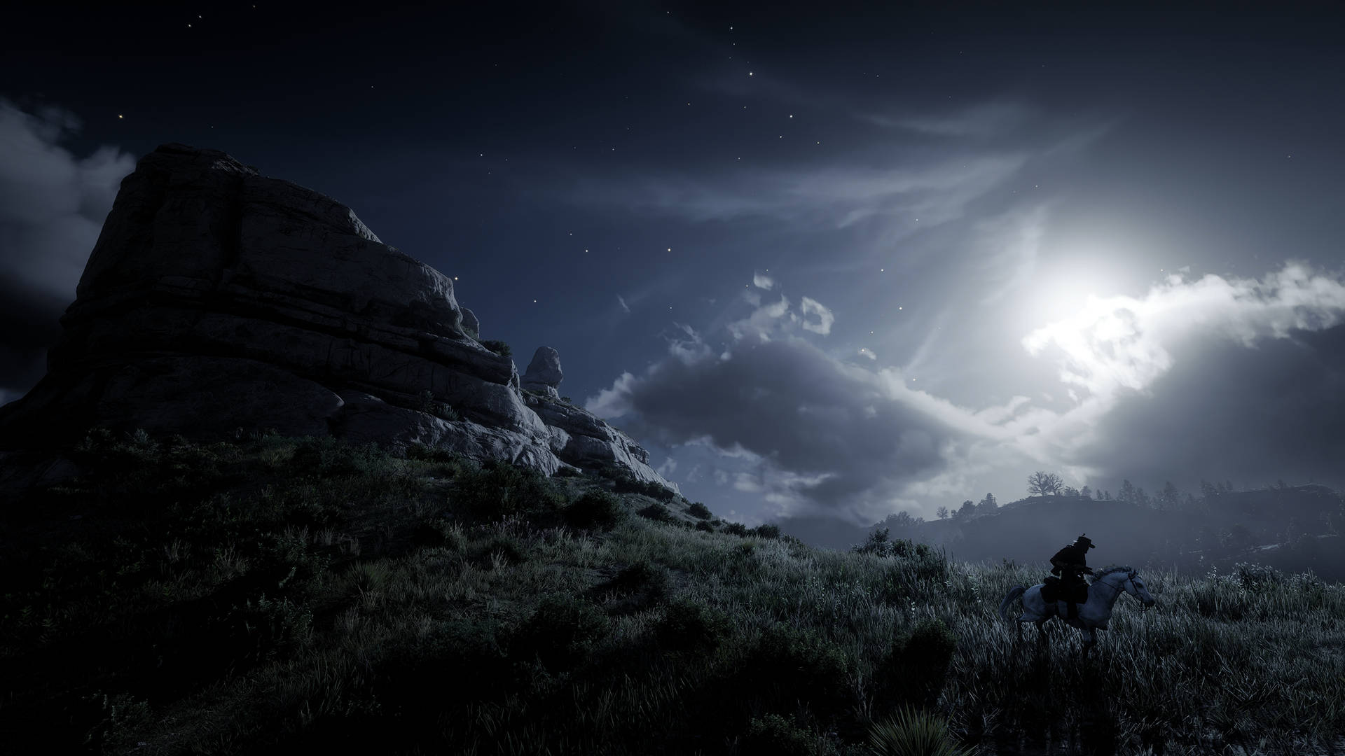 Red Dead Redemtion 2 桌布 壁紙 — 一個孤獨的騎手騎在馬背上，在月光照耀的天空、戲劇性的雲彩和星空下的岩石露頭襯托下形成剪影。