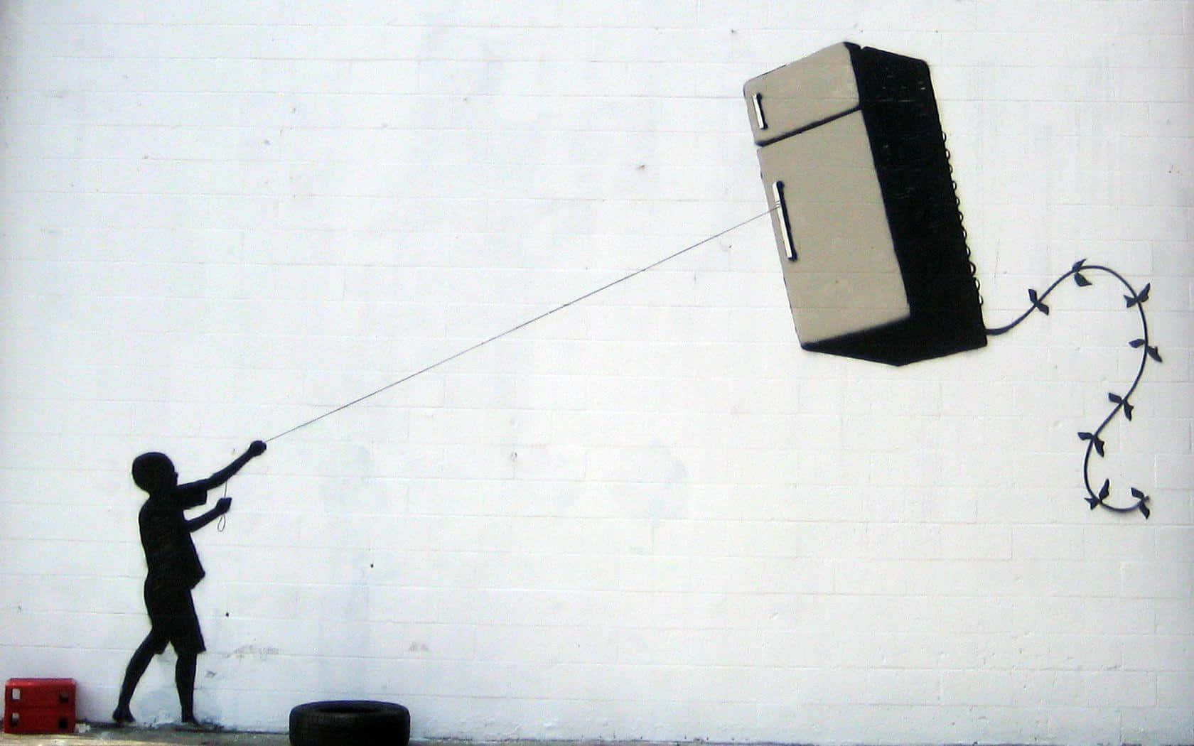 Banksy 桌布 壁紙 — 一個孩子的剪影放飛冰箱風箏，風箏線上有藤蔓垂下，背景是白色磚牆。