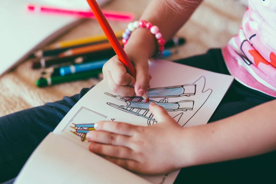 pencil 桌布 壁紙 — 一個孩子的手用紅色蠟筆為火箭上色，周圍散落著美術用品。