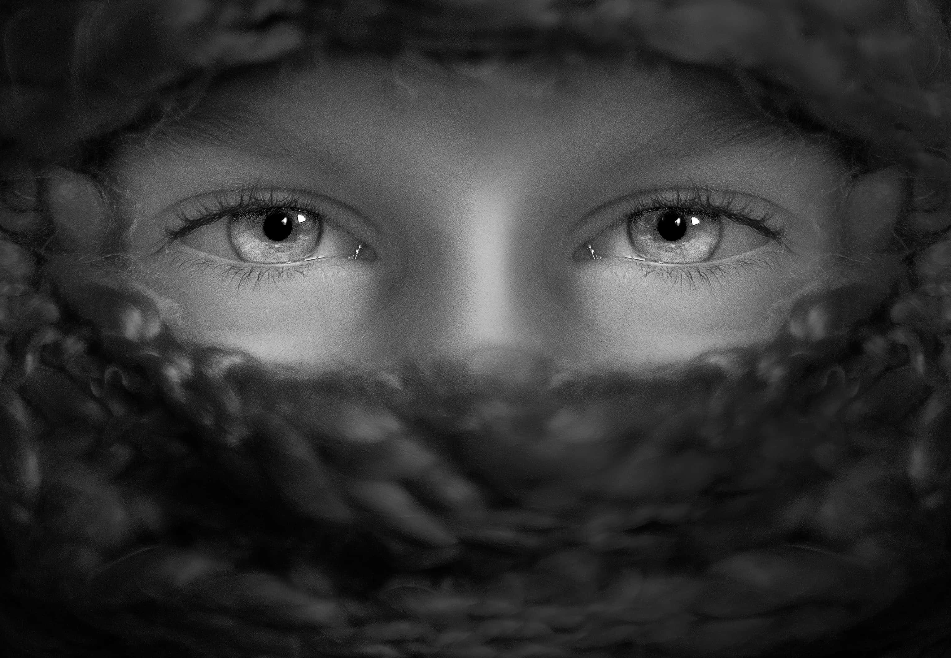 Eyes 桌布 壁紙 — 一個孩子銳利的眼睛透過厚編織帽窺視，呈現強烈的黑白肖像。