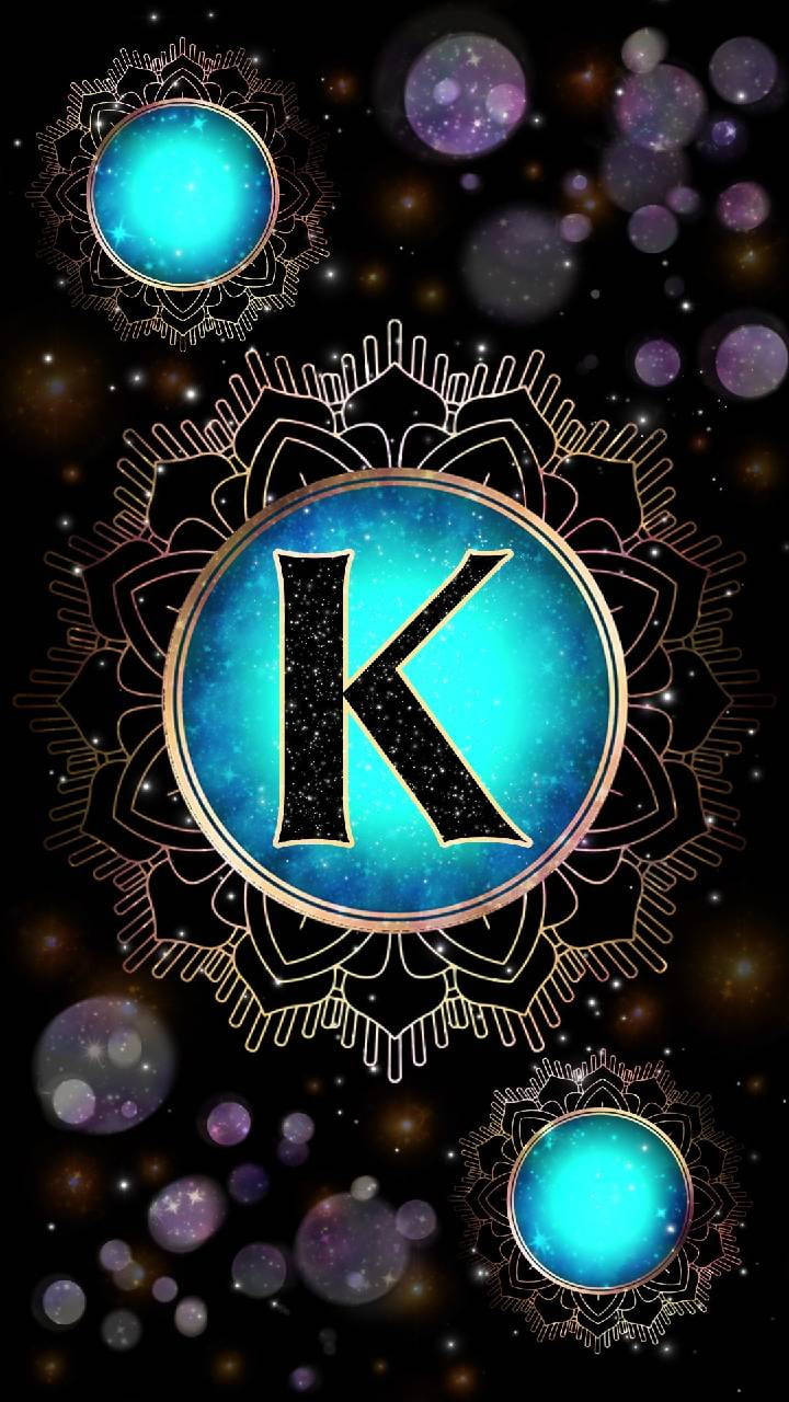 字母K動圖 桌布 壁紙 — 一個宇宙字母K，在發光的藍色球體中，周圍環繞著複雜的曼陀羅圖案和星形散景，背景為黑色。