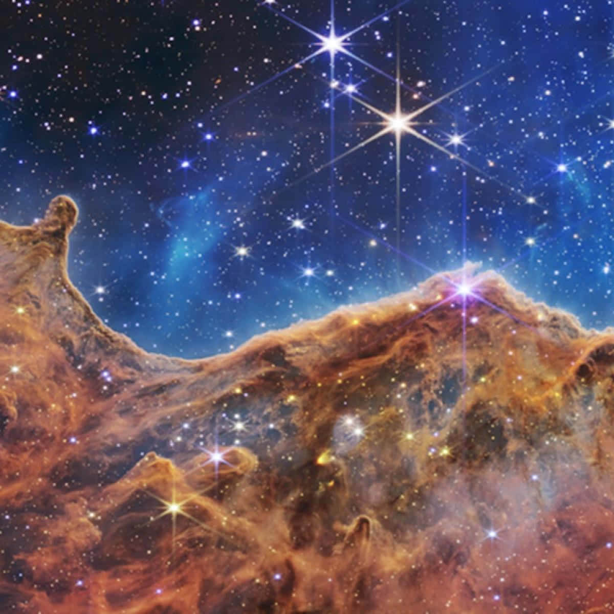 銀河 桌布 壁紙 — 一個宇宙星雲，帶有發光的橙色雲團和明亮的星星，背景是深藍色的星場。