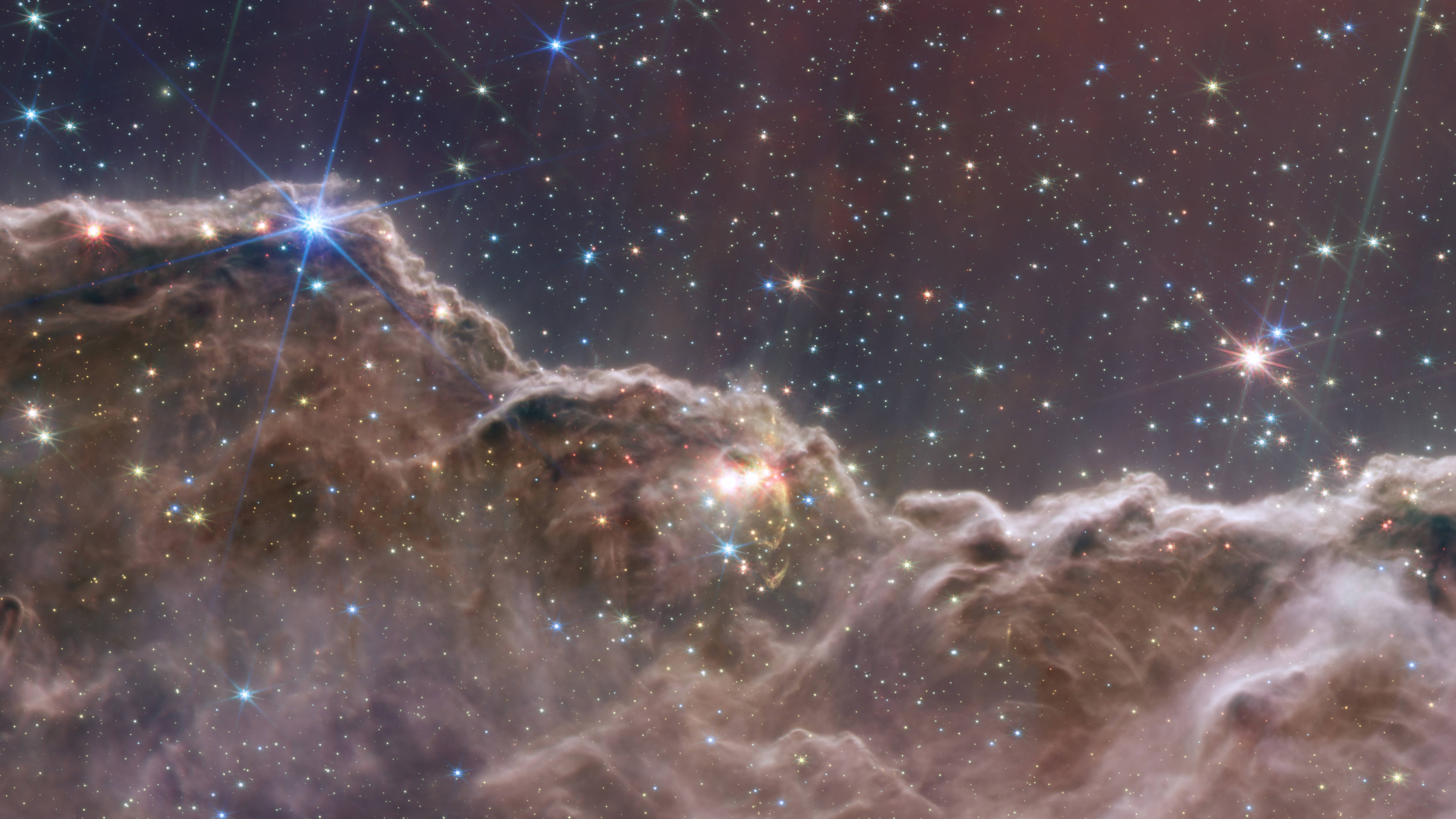桌布 壁紙 — 一個宇宙星雲，帶有發光的氣體雲和明亮的星星，背景是深邃的太空。