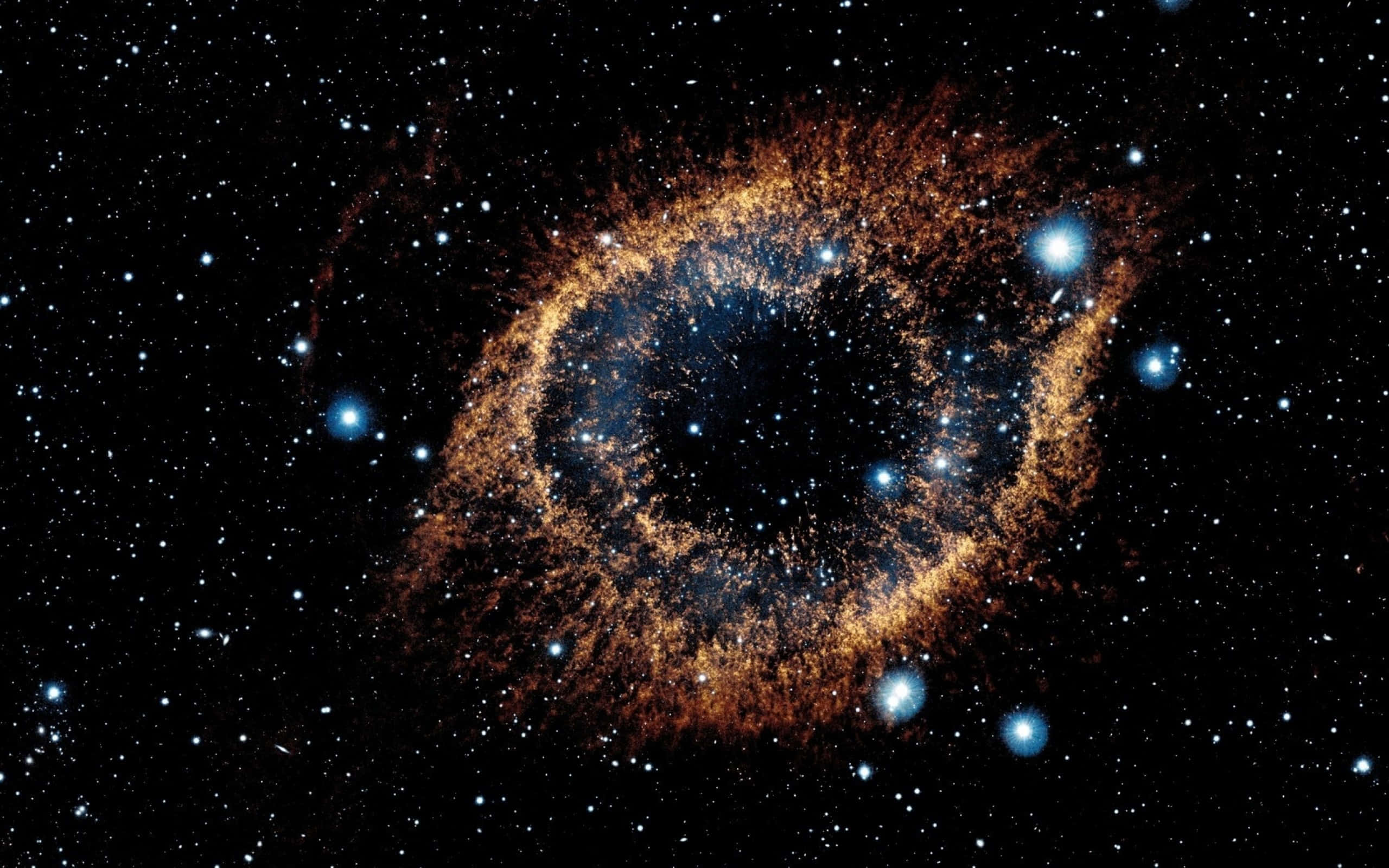 Stars 桌布 壁紙 — 一個宇宙星雲，金色橙色絲狀物圍繞黑暗中心旋轉，被明亮的藍色星星包圍，背景是黑色虛空。