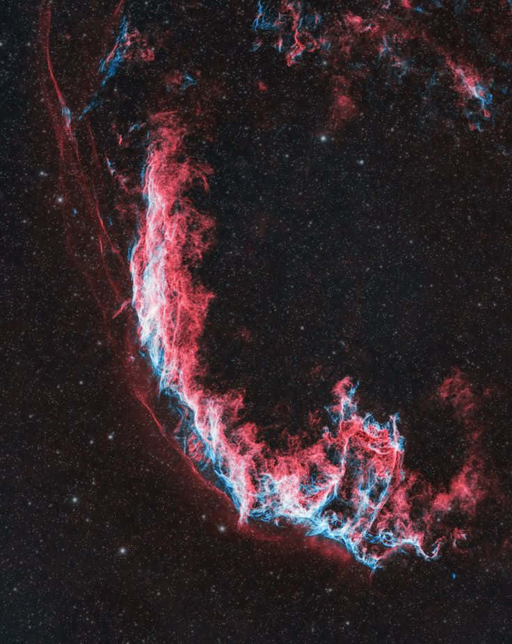 Interstellar Cloud 桌布 壁紙 — 一個宇宙星雲在佈滿星星的黑色虛空中發出鮮豔的紅色和藍色卷鬚光芒。