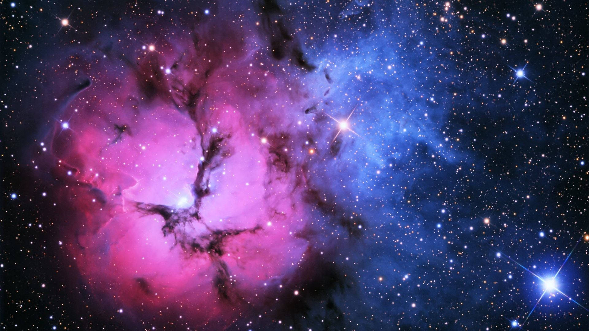 粉紅銀河 桌布 壁紙 — 一個宇宙星雲在充滿明亮星星的星場中旋轉，呈現鮮豔的粉紅色和藍色。