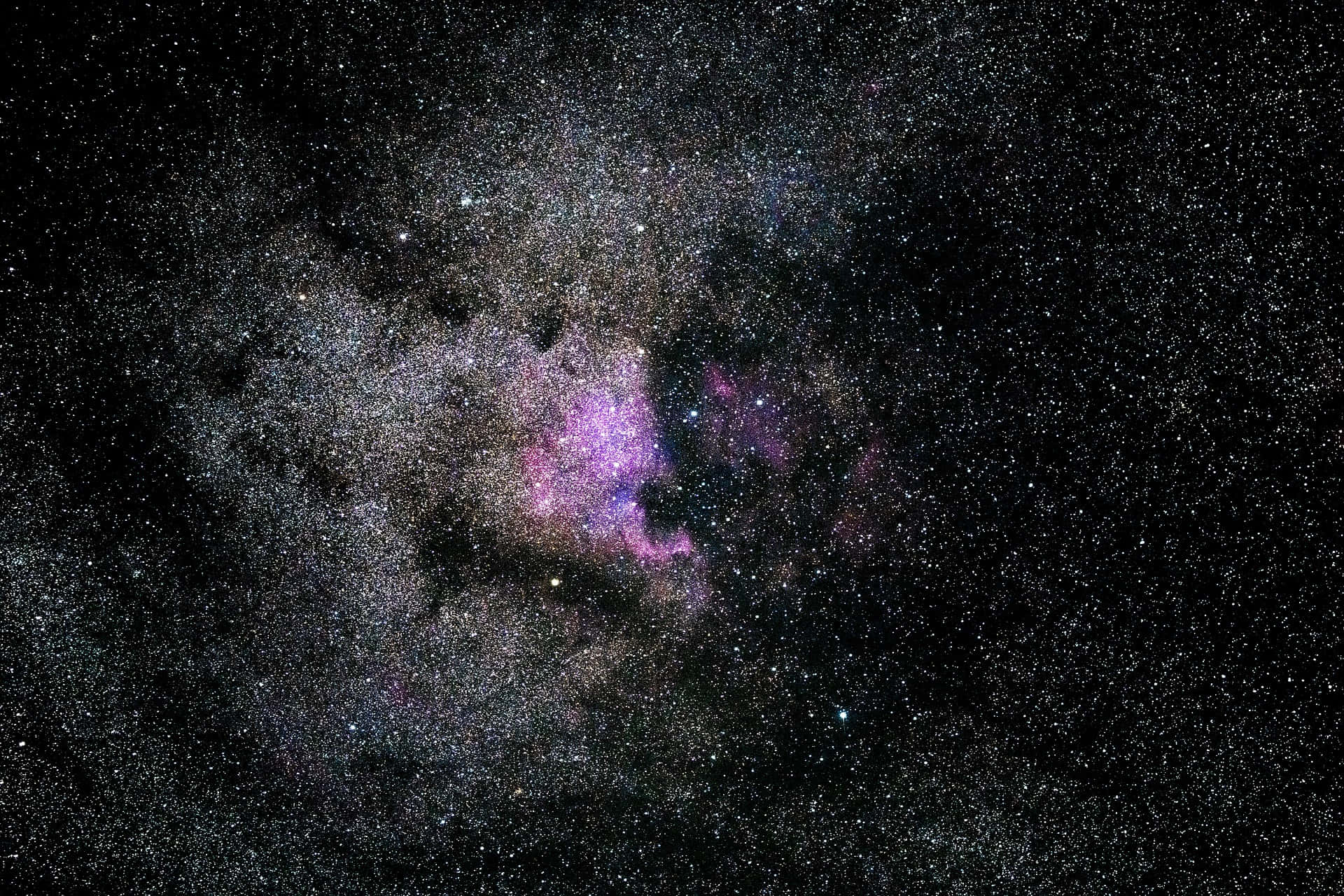 Dark Galaxy 桌布 壁紙 — 一個宇宙星雲在密集的恆星和黑暗宇宙塵埃背景下散發出充滿活力的紫色和粉紅色色調。