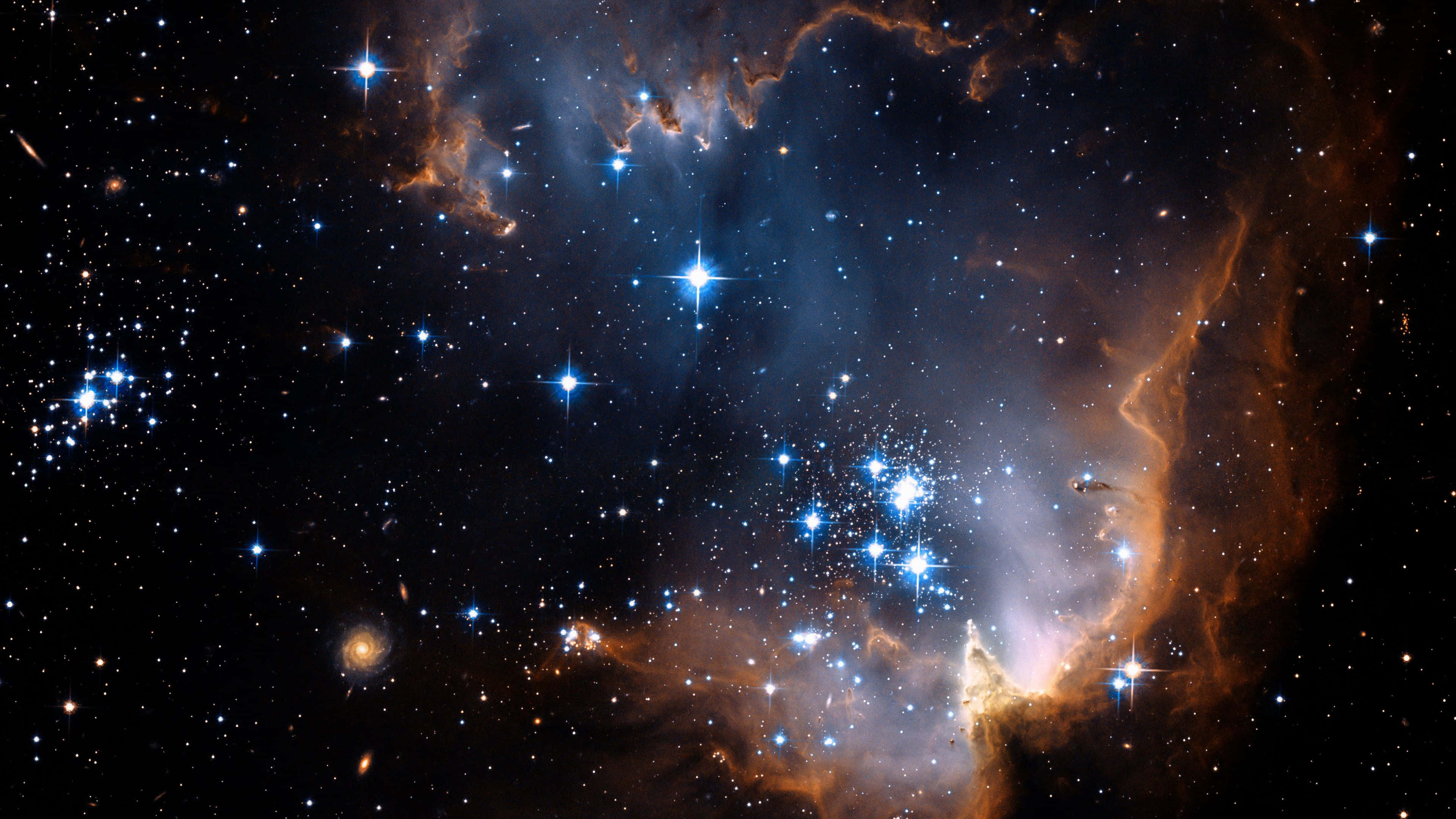 Stars 桌布 壁紙 — 一個宇宙星雲在星空中散發出鮮豔的橙色和藍色色調，呈現明亮的恆星和旋轉的氣體雲。