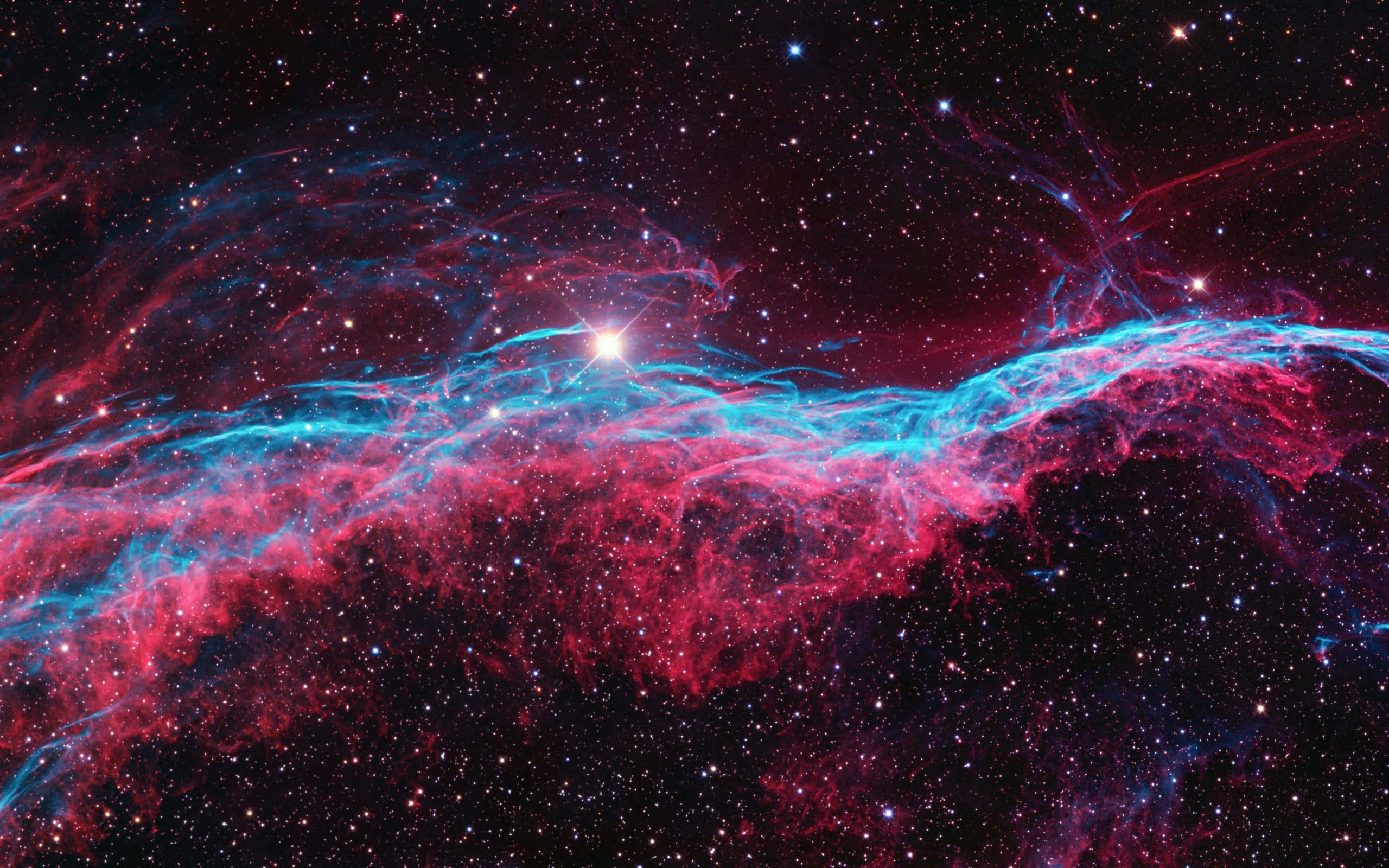 紅色動圖 桌布 壁紙 — 一個宇宙星雲在星空背景下以鮮豔的紅色和電光藍色旋轉，一顆明亮的中心恆星照亮了宇宙塵埃。