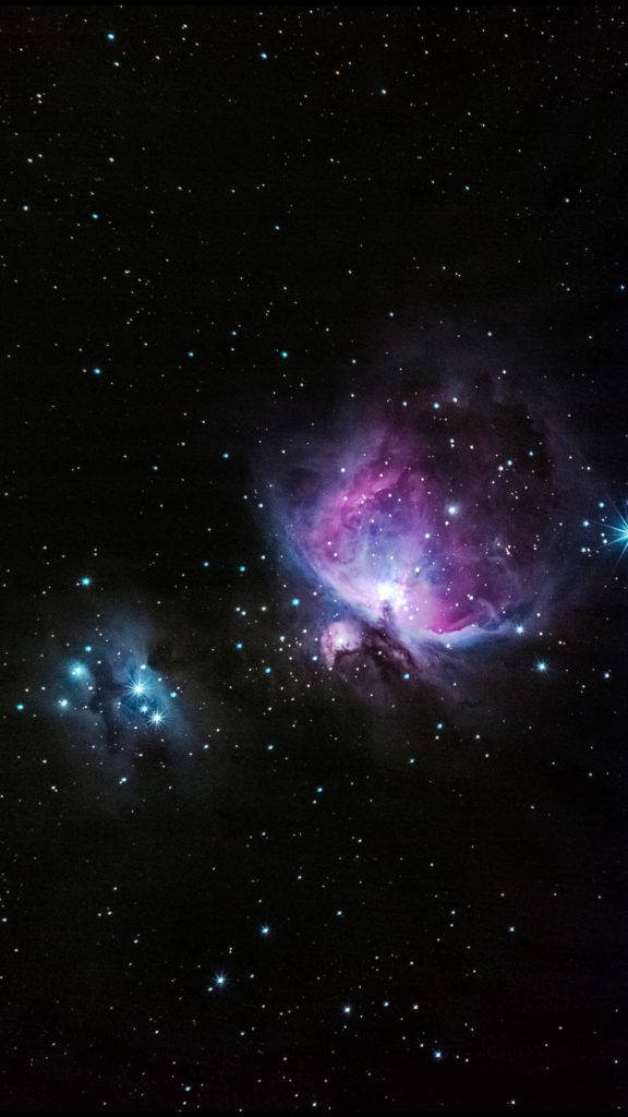 blue space phone 桌布 壁紙 — 一個宇宙星雲在深空的星場背景下散發出充滿活力的紫色和藍色色調。