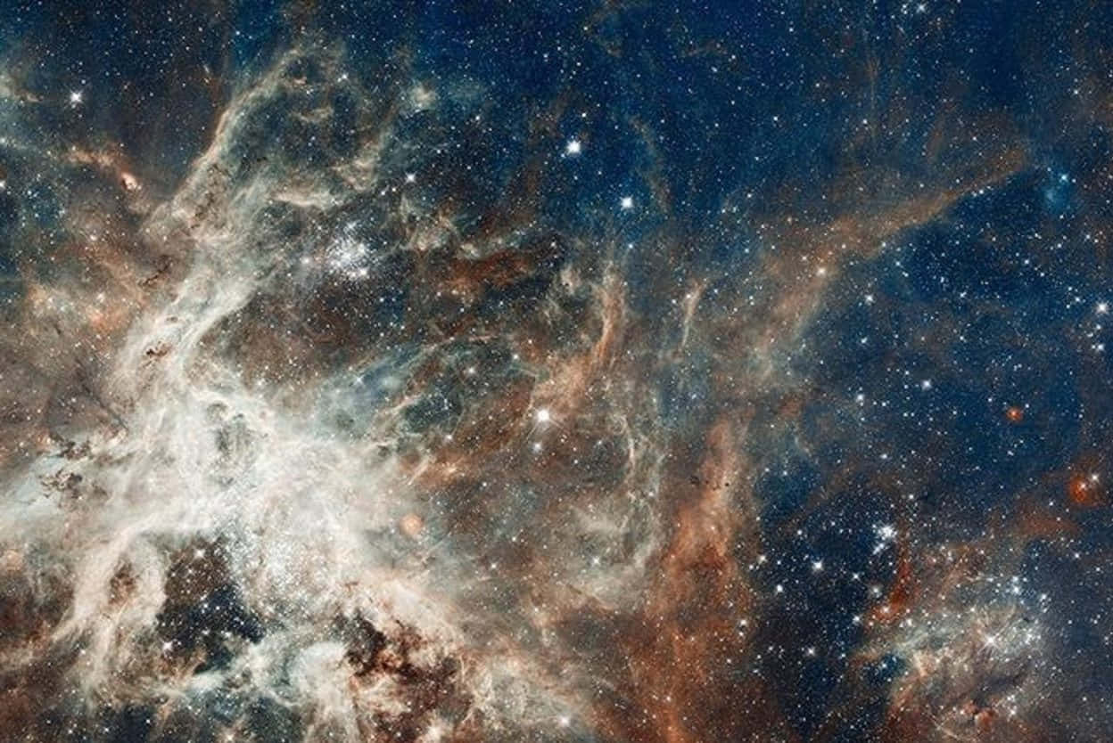 Starry Sky 桌布 壁紙 — 一個宇宙星雲在深藍色星場中旋轉，散發著發光的橙色和白色氣體。