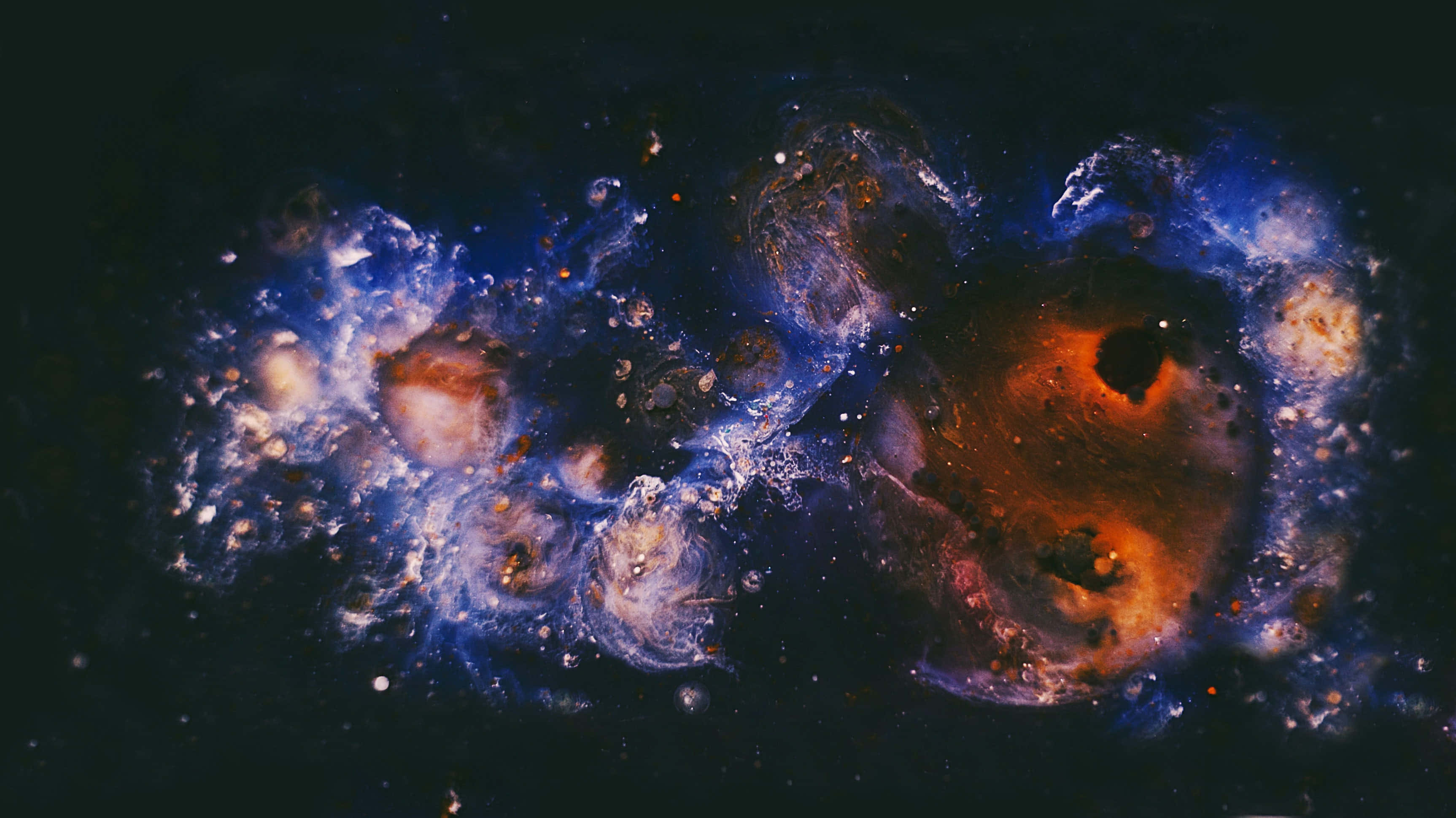 銀河 桌布 壁紙 — 一個宇宙星雲在深邃的黑色虛空中旋轉，充滿鮮豔的藍色和火熱的橙色雲團，點綴著遙遠的星星。