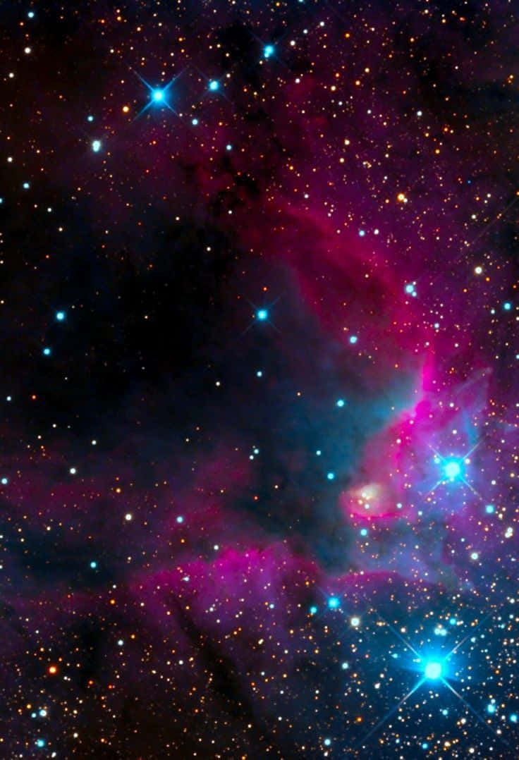 閃爍 桌布 壁紙 — 一個宇宙星雲在深邃的黑色虛空中旋轉，充滿鮮豔的洋紅色和電藍色氣體雲，點綴著閃爍的明亮星星。
