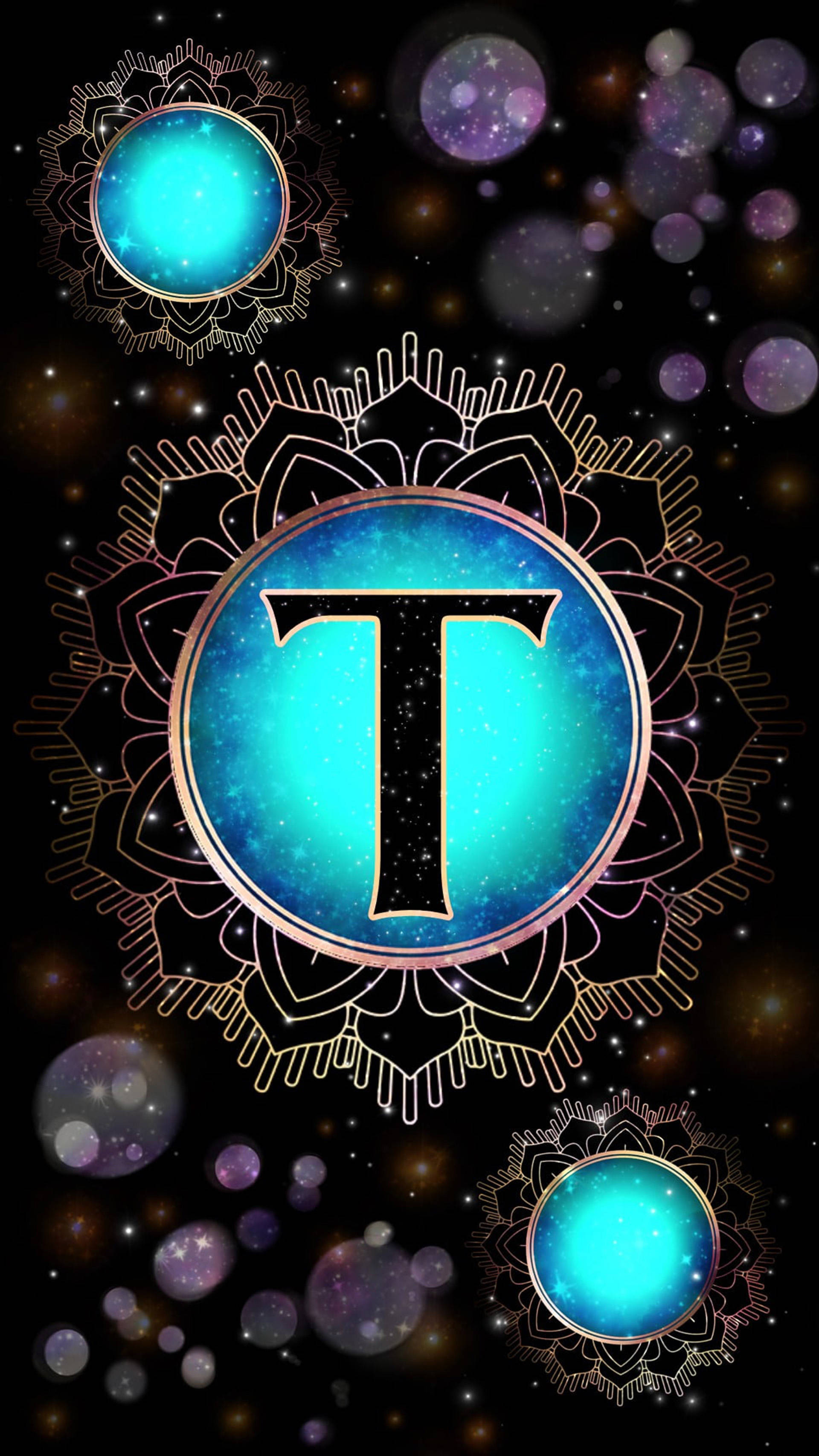 t 桌布 壁紙 — 一個宇宙曼陀羅，中心有一個發光的藍色「T」，周圍環繞著星狀球體和金色花絲，背景是黑暗的太空。
