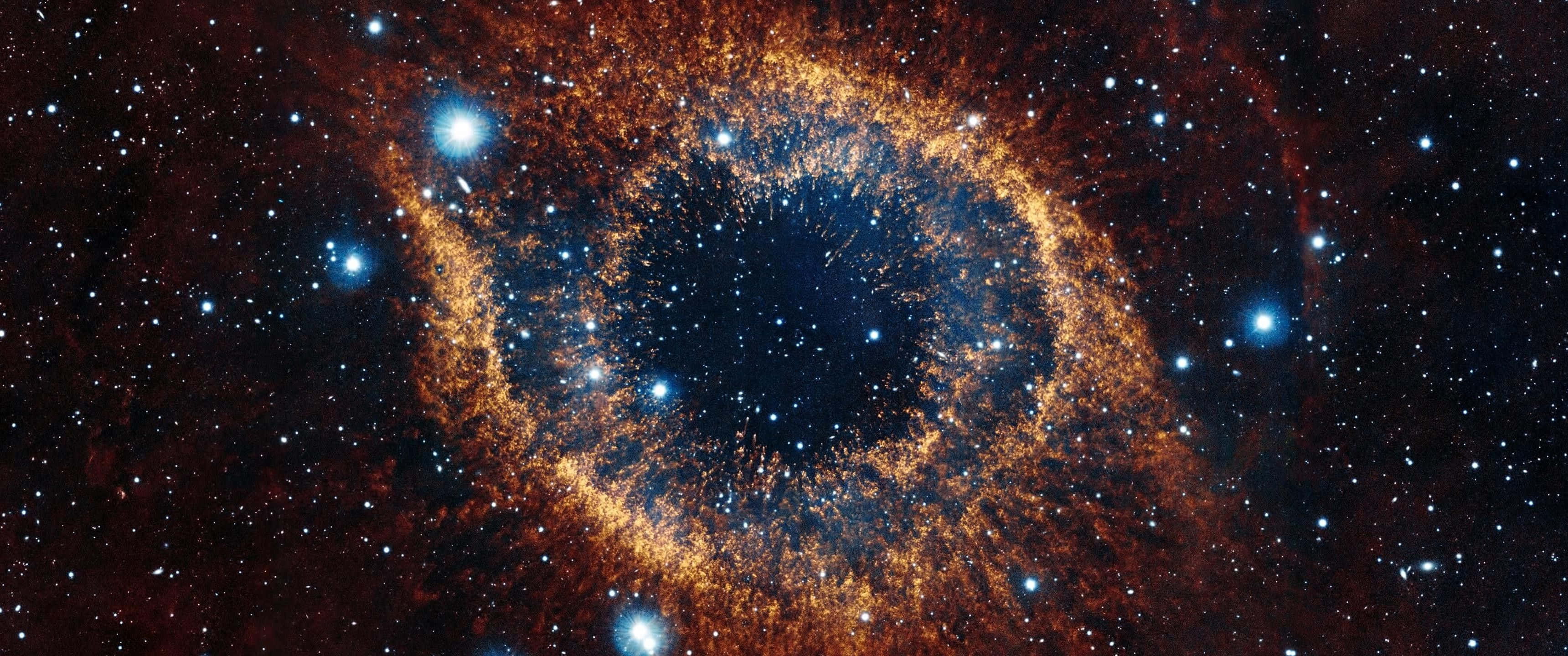彩色動圖 桌布 壁紙 — 一個宇宙眼形星雲在星空中散發出火橙色和深藍色的光芒。