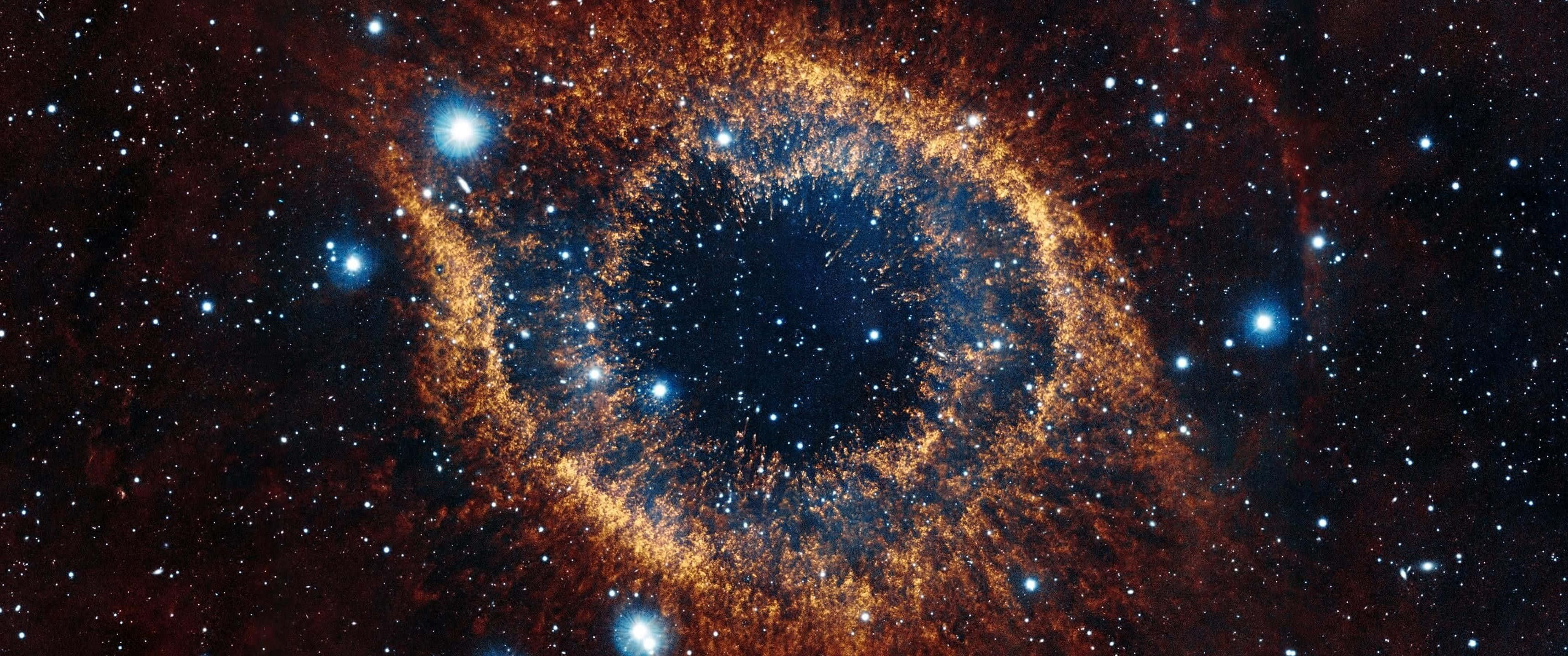 高清 桌布 壁紙 — 一個宇宙眼形星雲在星空中散發出火橙色和深藍色的光芒。