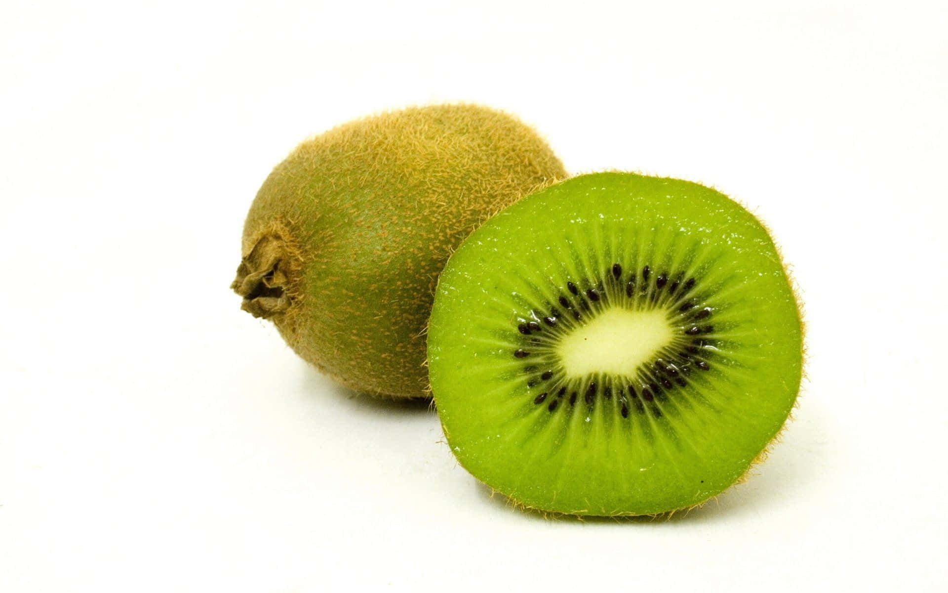 Kiwi 桌布 壁紙 — 一個完整及切半的奇異果，展現出鮮綠色果肉和黑色種子，背景為純白色。