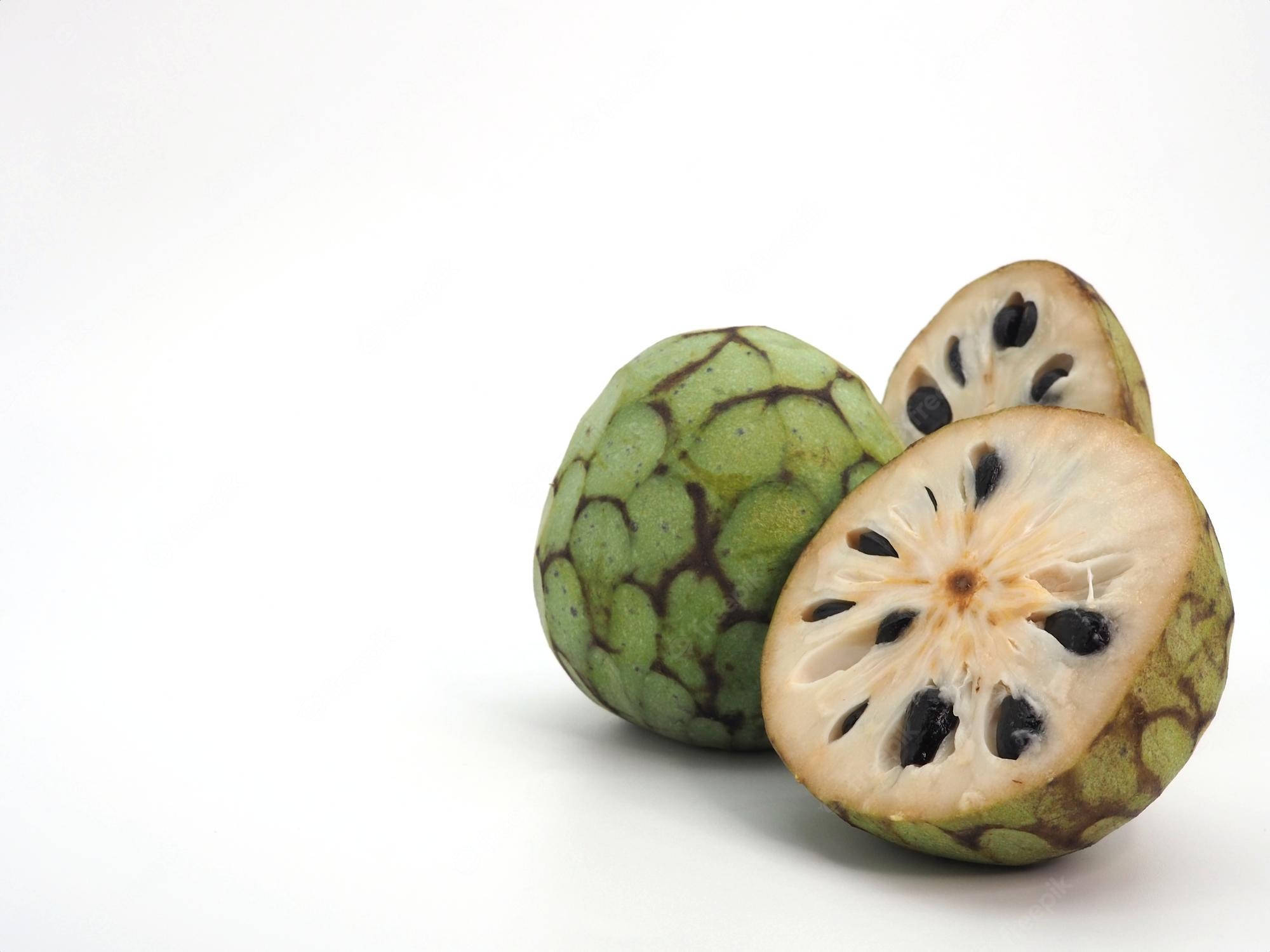 Fruit 桌布 壁紙 — 一個完整和切開的綠色刺果番荔枝，帶有奶油狀果肉和黑色種子，背景為純白色。