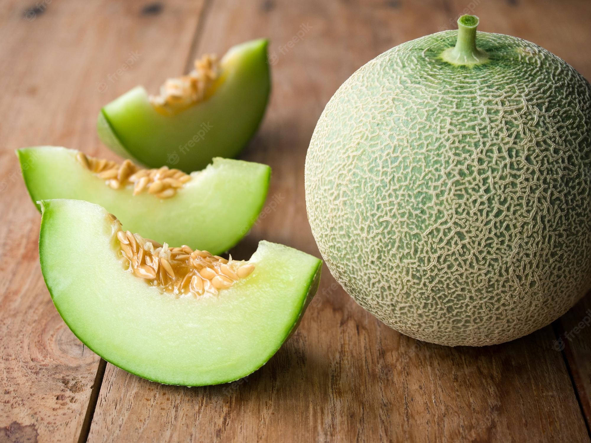 Fruits 桌布 壁紙 — 一個完整和切開的青瓜（蜜瓜）放在質樸的木質表面上，可見種子。