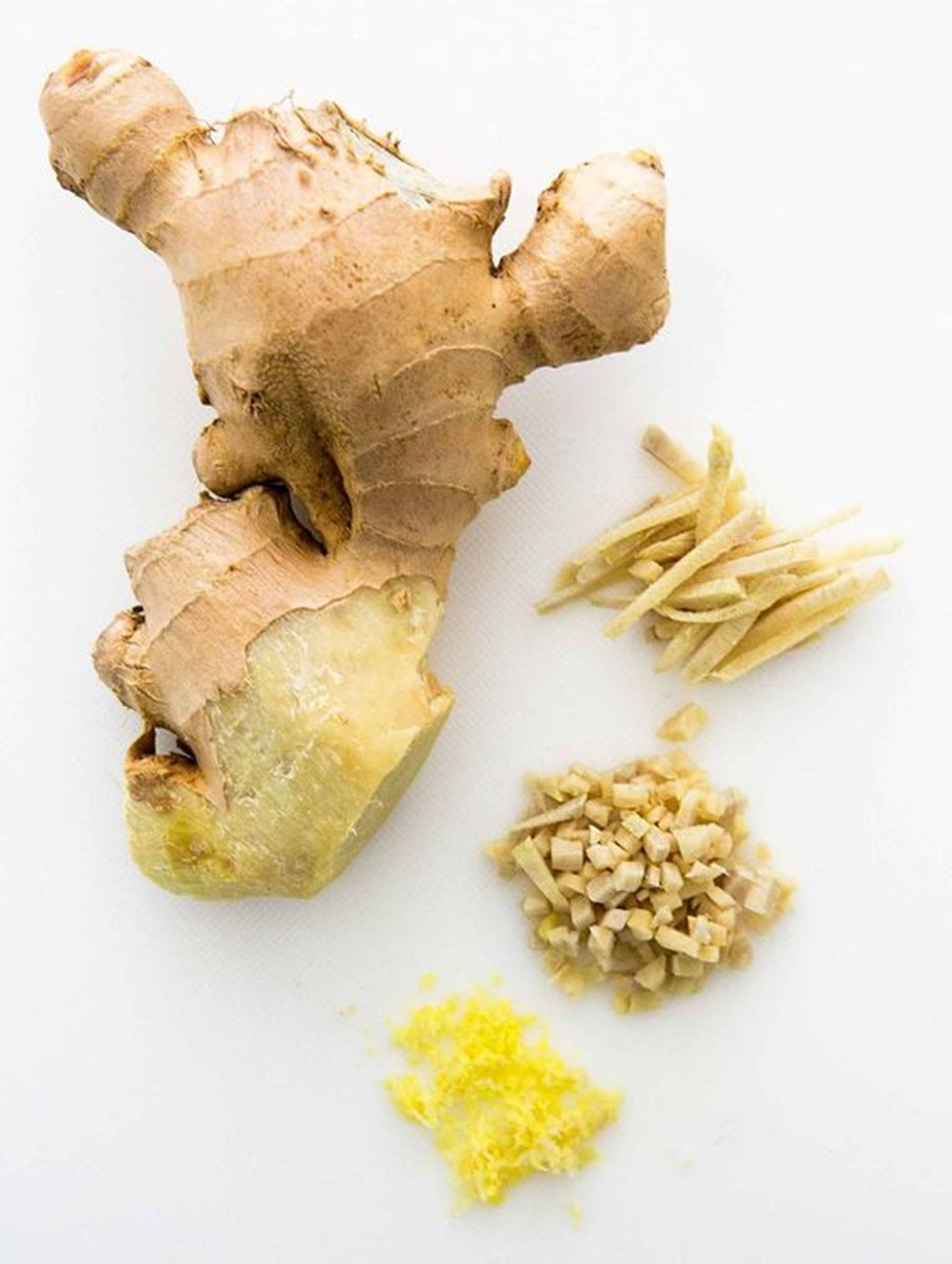 Ginger 桌布 壁紙 — 一個完整的生薑根，帶有去皮的部分，以及一堆切成絲和磨碎的生薑，放在白色表面上。