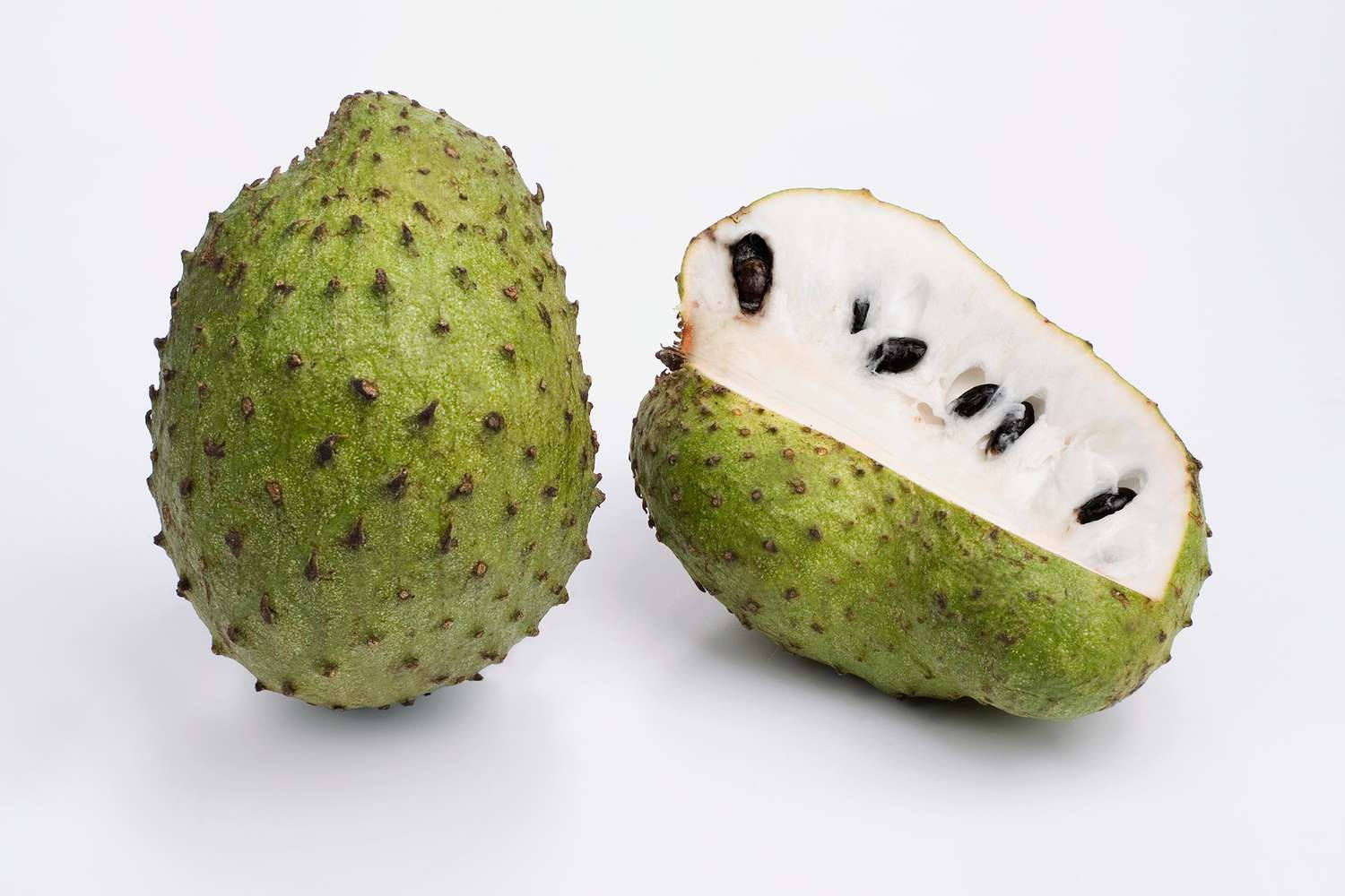 Fruits 桌布 壁紙 — 一個完整的綠色多刺刺果實旁邊放著切半的另一半，露出奶油白色果肉和黑色種子，背景是純白色。