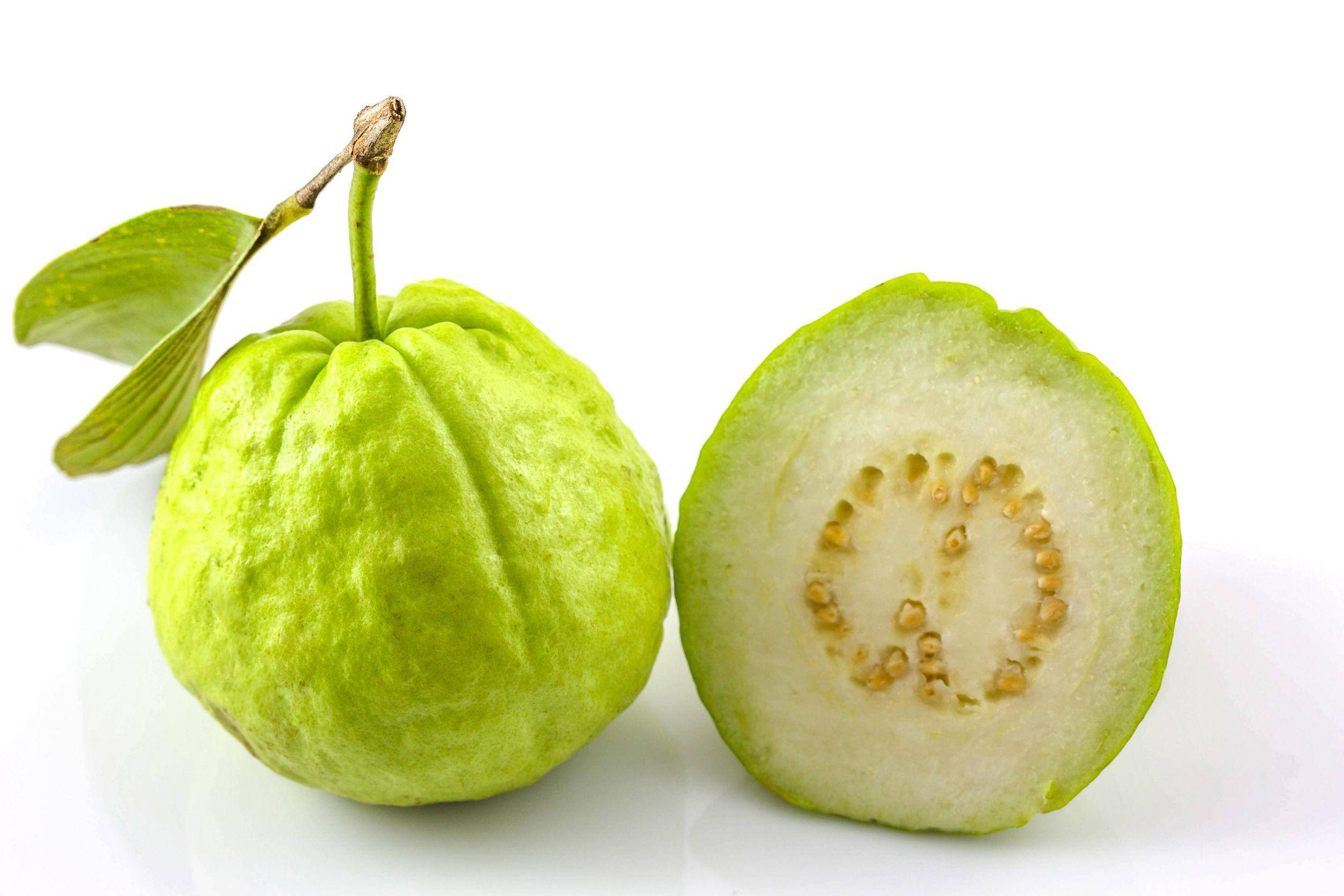Fruit 桌布 壁紙 — 一個完整的綠色芭樂連葉，旁邊是一個切半的芭樂，露出淡色果肉和中央的種子環，背景為白色。