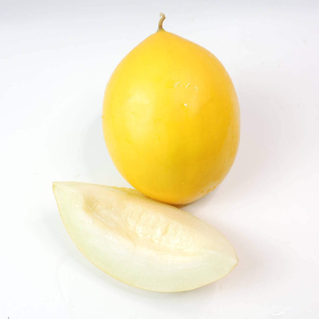 Fruit 桌布 壁紙 — 一個完整的黃色哈密瓜和一塊淡色的切片放在潔白的表面上，展示多汁的內部及光滑的外皮。