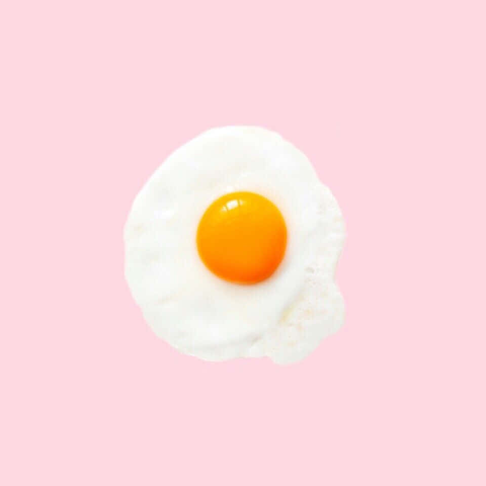 Egg 桌布 壁紙 — 一個完美煎好的太陽蛋，鮮橙色蛋黃位於柔軟粉紅色背景中央。
