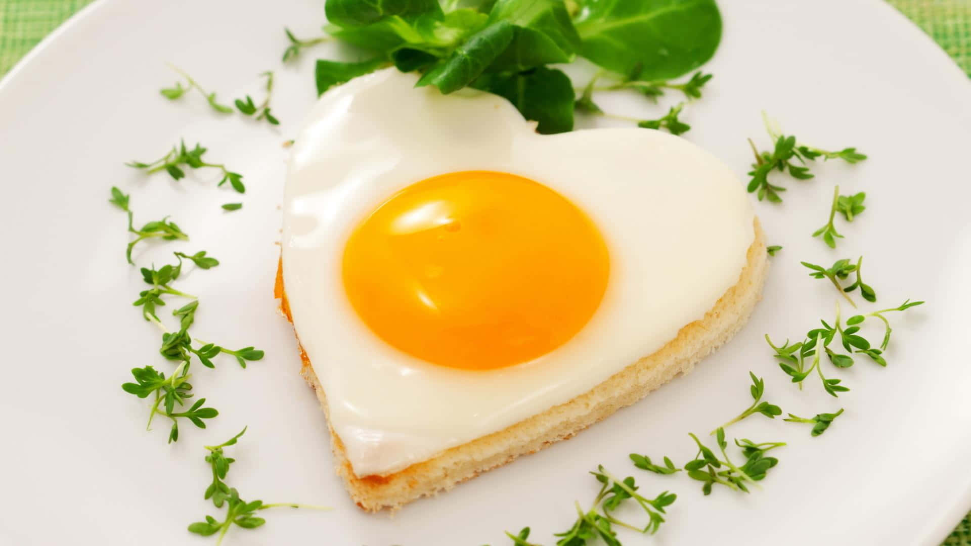 Egg 桌布 壁紙 — 一個完美煎成心形的雞蛋，帶有鮮豔的蛋黃，放在一片吐司上，飾以新鮮百里香，置於白色盤中。