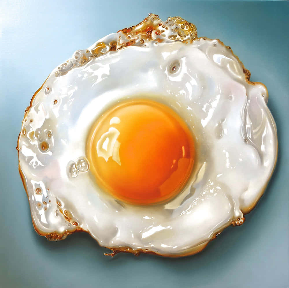 Egg 桌布 壁紙 — 一個完美煎蛋，帶有鮮豔的橙色蛋黃和酥脆的金色邊緣，放在柔和的藍色背景上。