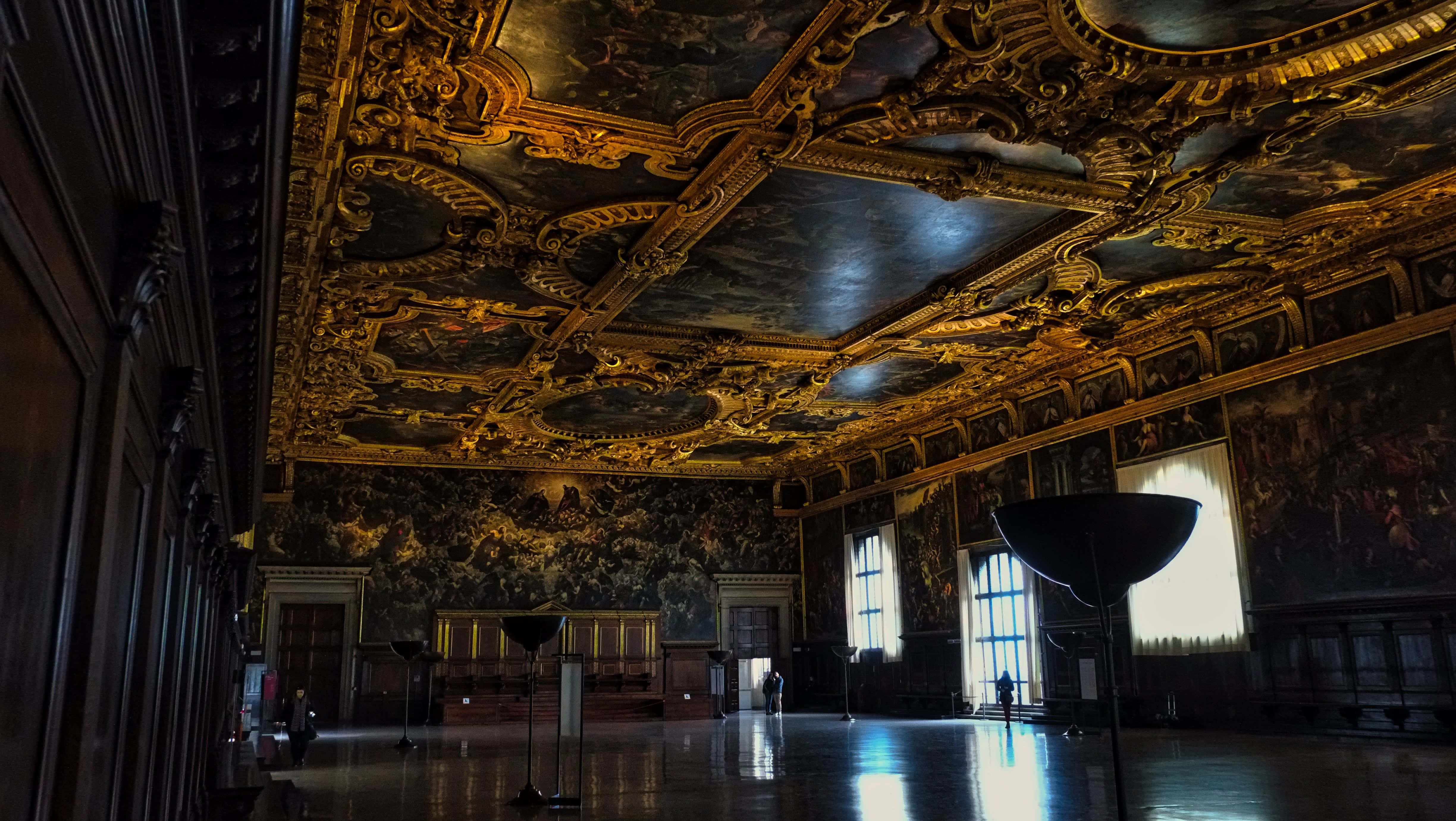 Ballroom 桌布 壁紙 — 一個宏偉昏暗的大廳，擁有華麗鍍金的天花板壁畫和大理石地板，反射著高窗透進的柔和光線。