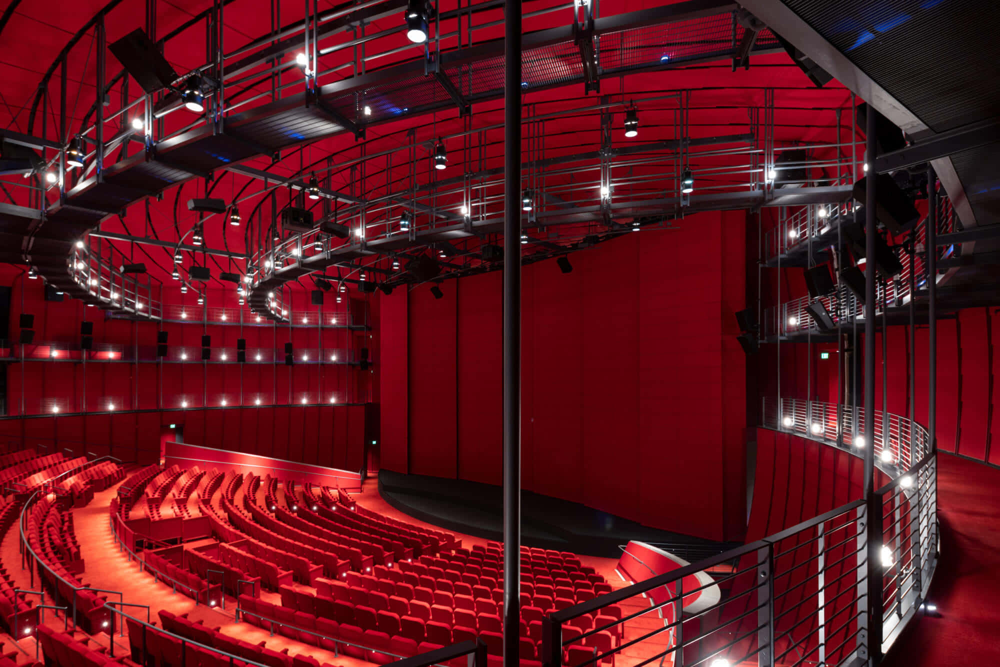 Theater 桌布 壁紙 — 一個宏偉的劇院，擁有寬闊的紅色座位和暴露的舞台設備，在溫暖的聚光燈下。