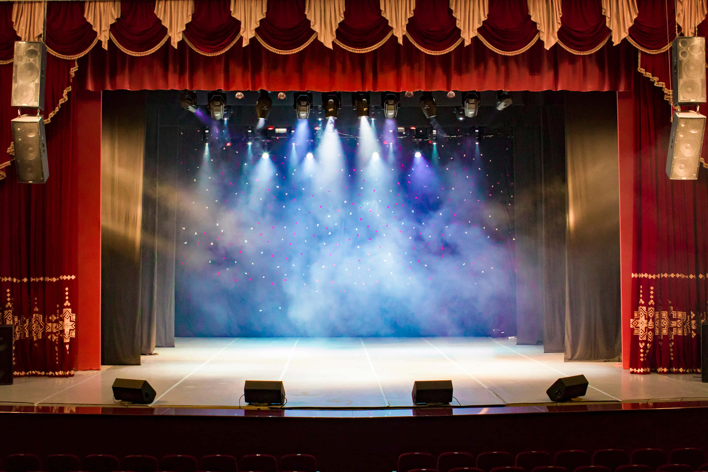 Stage 桌布 壁紙 — 一個宏偉的劇院舞台，沐浴在藍色聚光燈和旋轉煙霧中，下方是豪華的紅色帷幕。