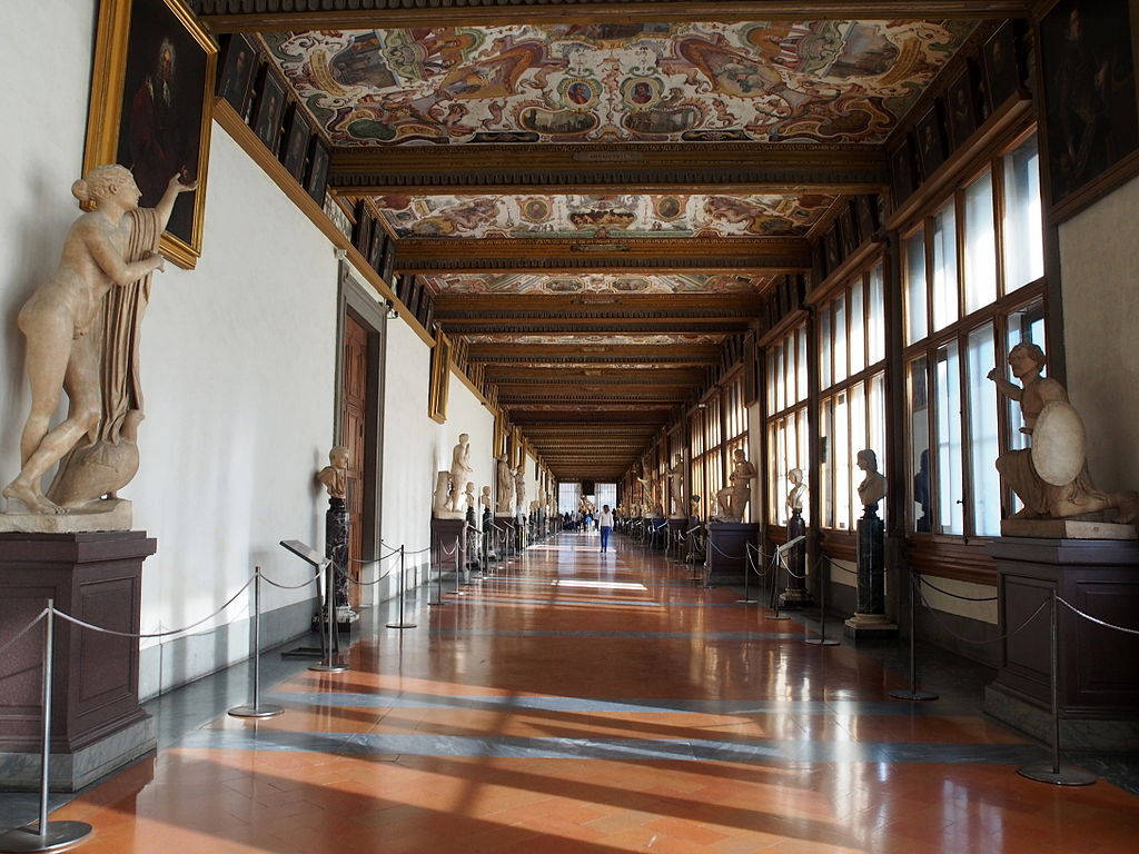 Museum 桌布 壁紙 — 一個宏偉的博物館畫廊，古典雕像排列在拋光地板上，上方是彩繪天花板，沐浴在自然光中。