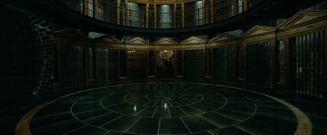 The Ministry Of Magic 桌布 壁紙 — 一個宏偉的圓形圖書館，擁有深色石地板和高聳的書架，光線昏暗。