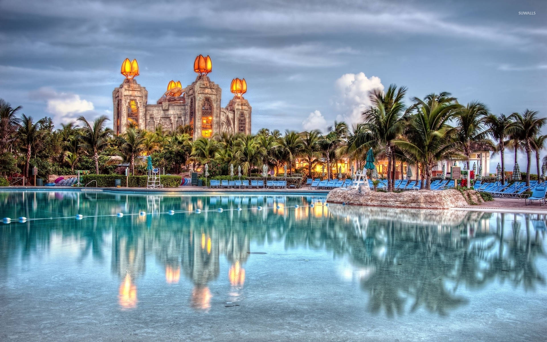 Nassau Bahamas 桌布 壁紙 — 一個宏偉的度假村泳池倒映著一座雄偉的城堡式建築，燈籠在暮色中閃閃發光。