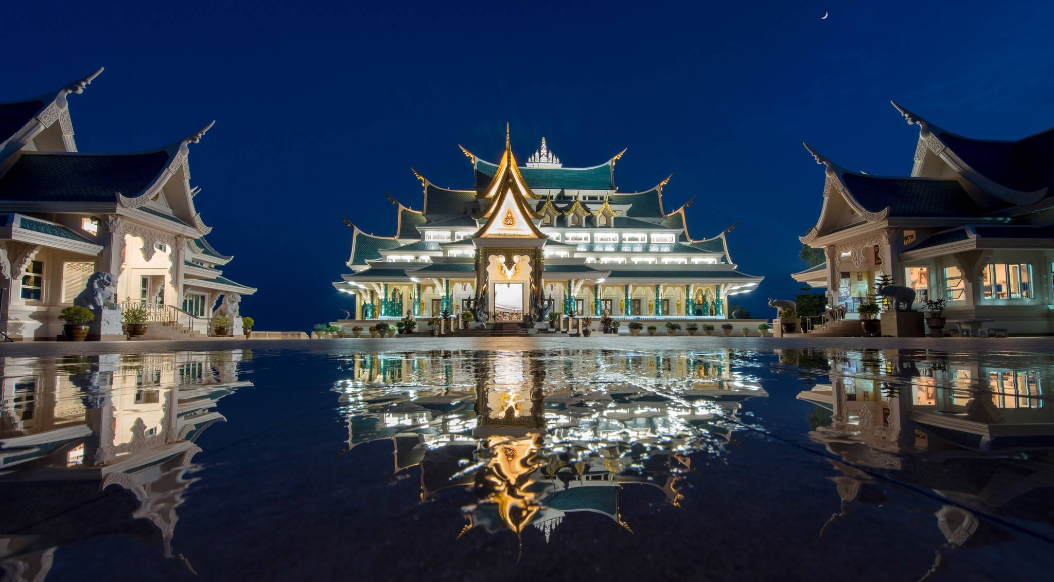 泰國 桌布 壁紙 — 一個宏偉的泰國寺廟建築群在夜晚被照亮，完美地倒映在月光下的平靜水池中。