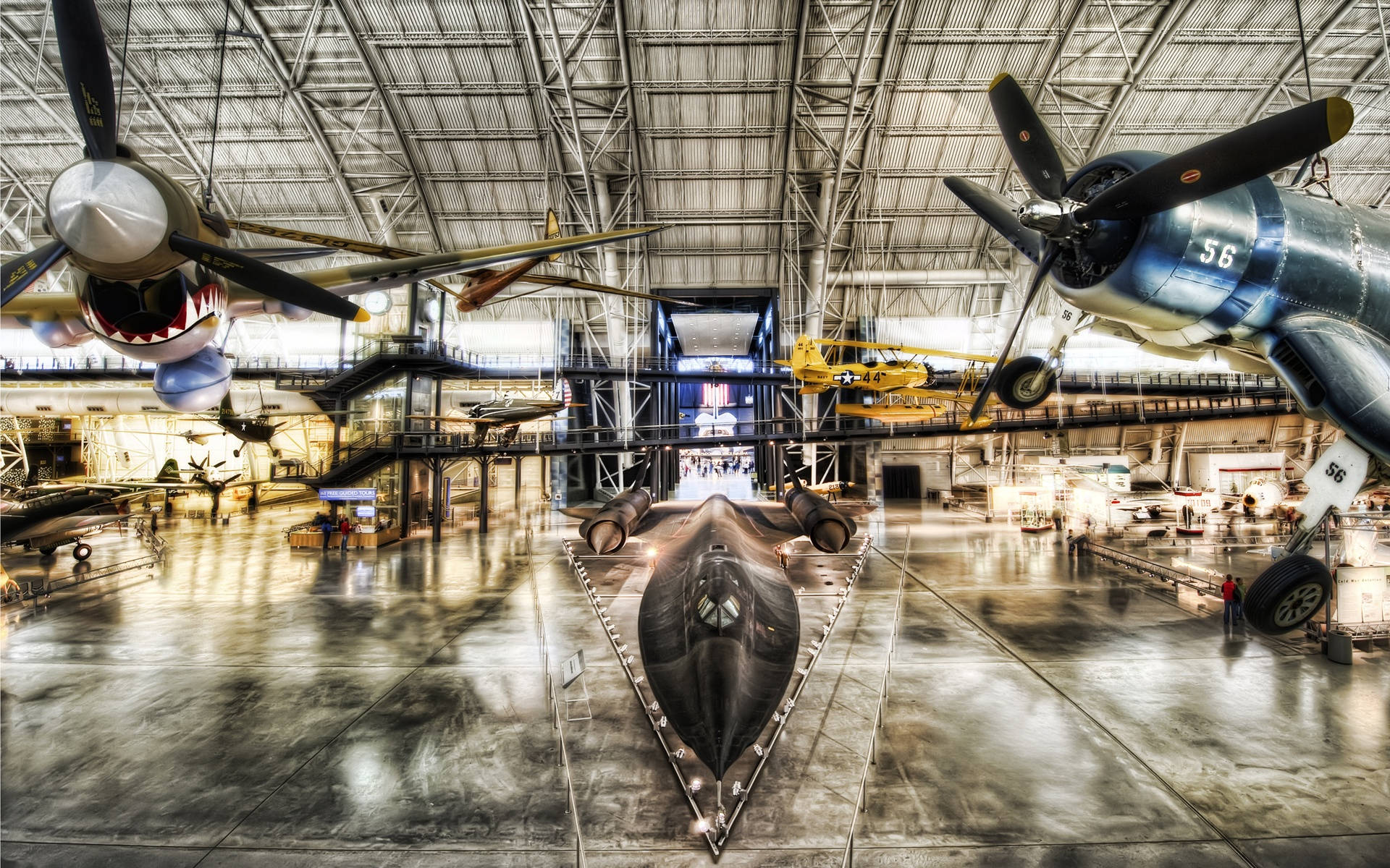 Smithsonian 桌布 壁紙 — 一個宏偉的航空博物館大廳，頭頂懸掛著復古戰鬥機，中央拋光地板上停放著一架時尚的黑色隱形轟炸機。