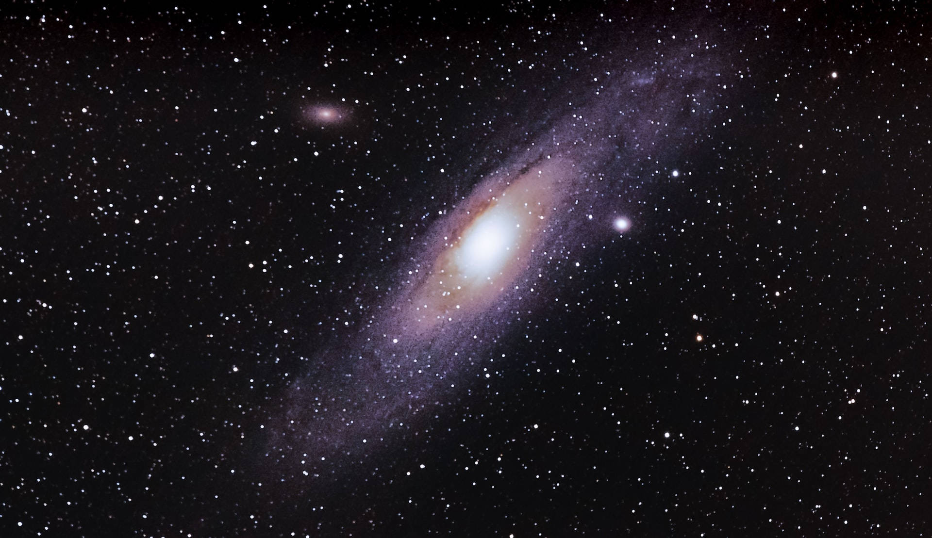 夜空 桌布 壁紙 — 一個宏偉的螺旋星系，明亮的核心和旋轉的臂在星場中閃耀。