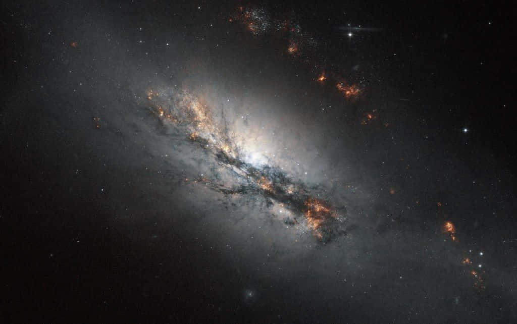 Galactic Center 桌布 壁紙 — 一個宏偉的螺旋星系在佈滿星空的宇宙虛空中旋轉，散發著發光的橙色和白色星雲。