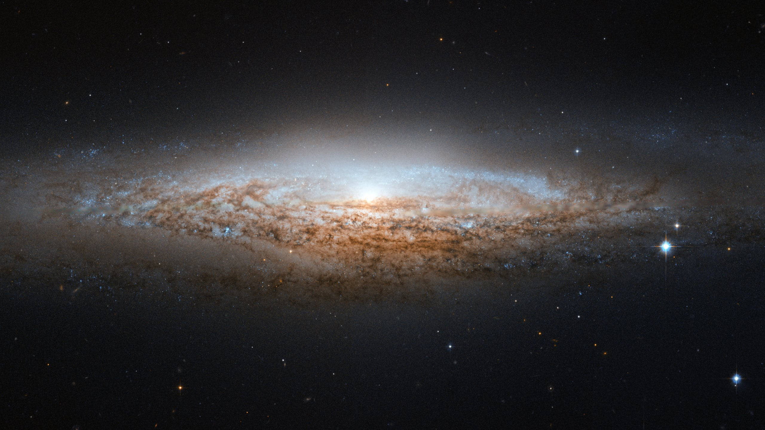 銀河 桌布 壁紙 — 一個宏偉的螺旋星系在佈滿星辰的宇宙虛空中閃耀著金色和藍色的色調。