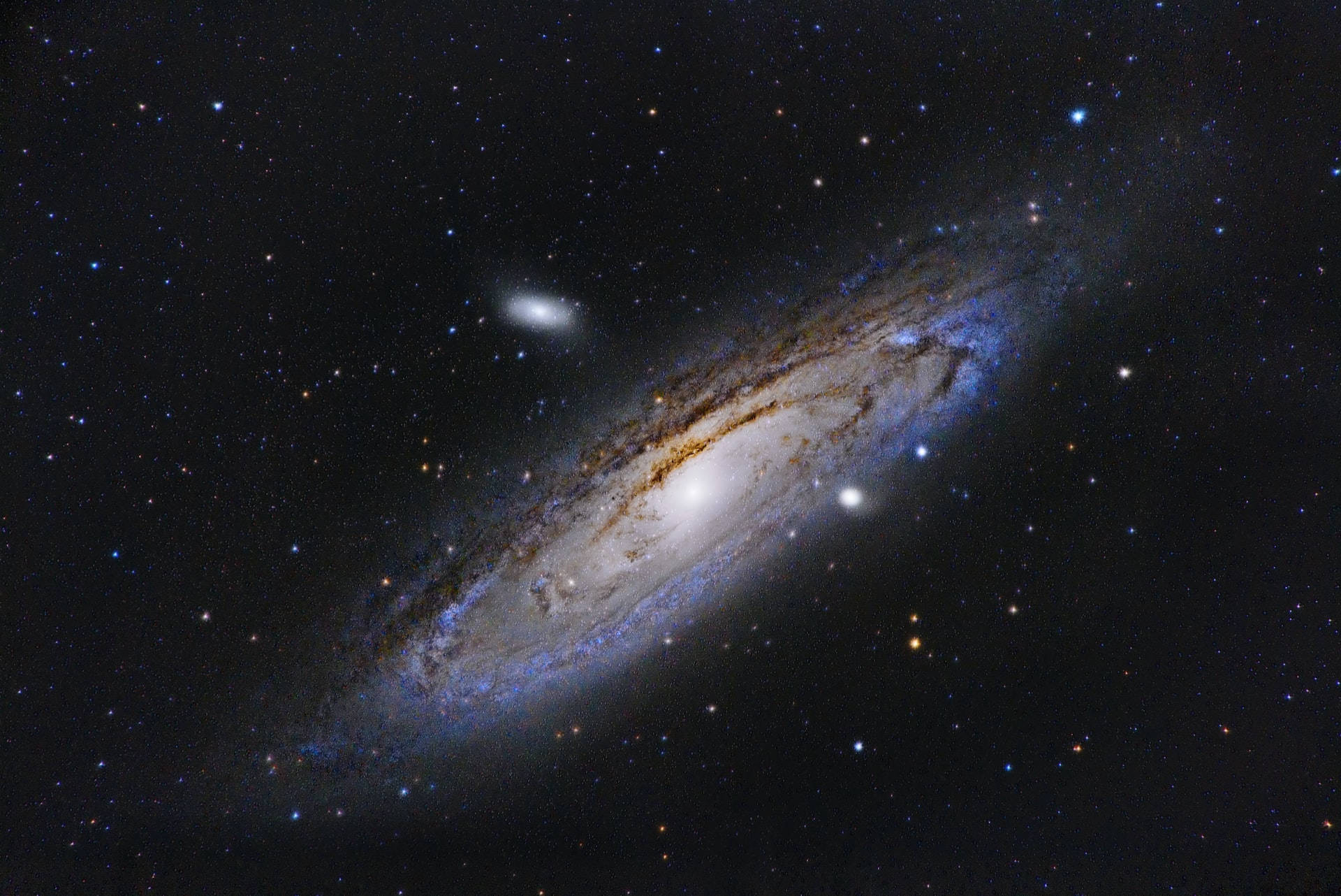 Stars 桌布 壁紙 — 一個宏偉的螺旋星系在深空的星場中發出藍色和金色的旋臂光芒。